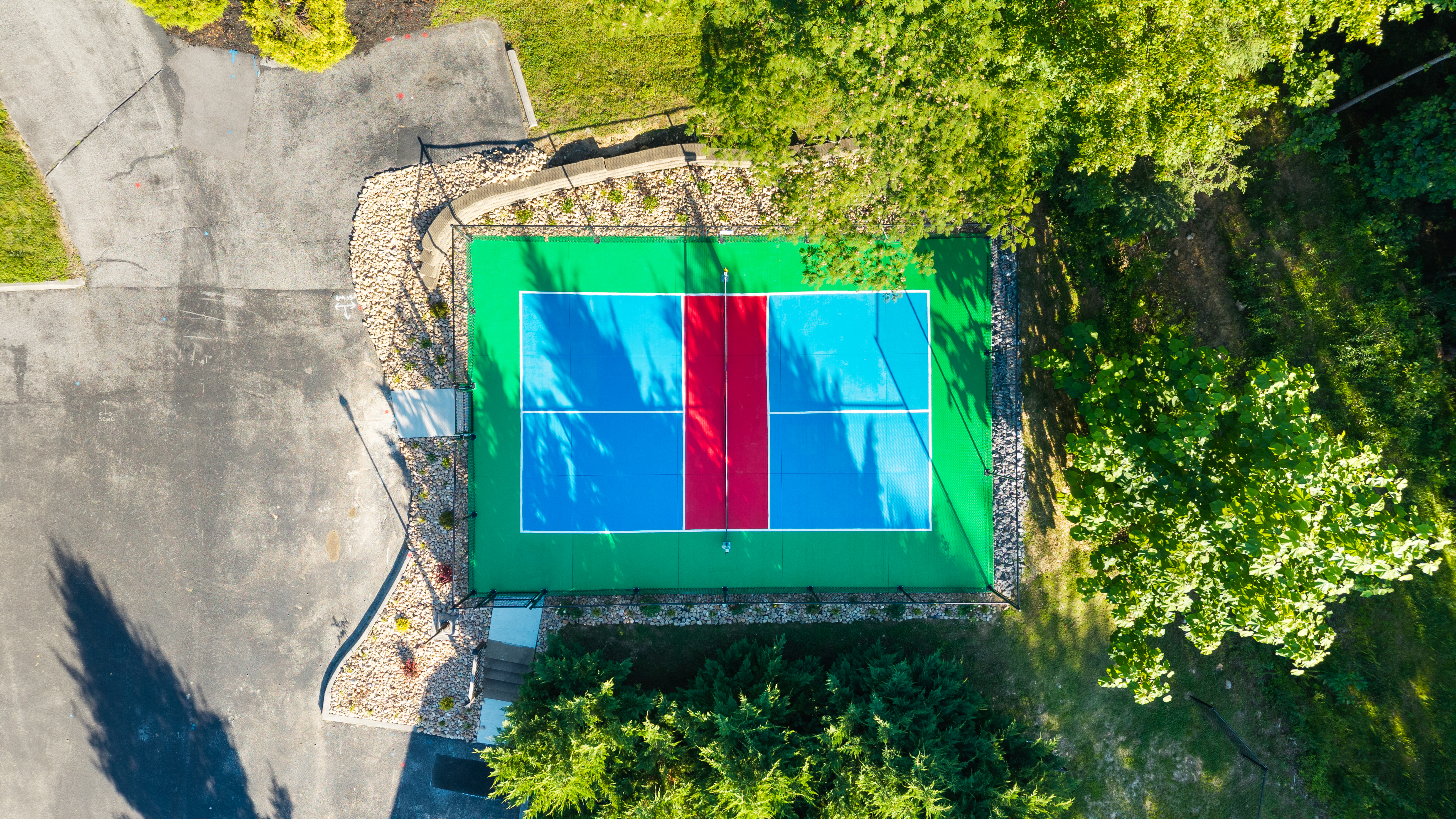 An overhead view of the shared community pickleball court among the trees.