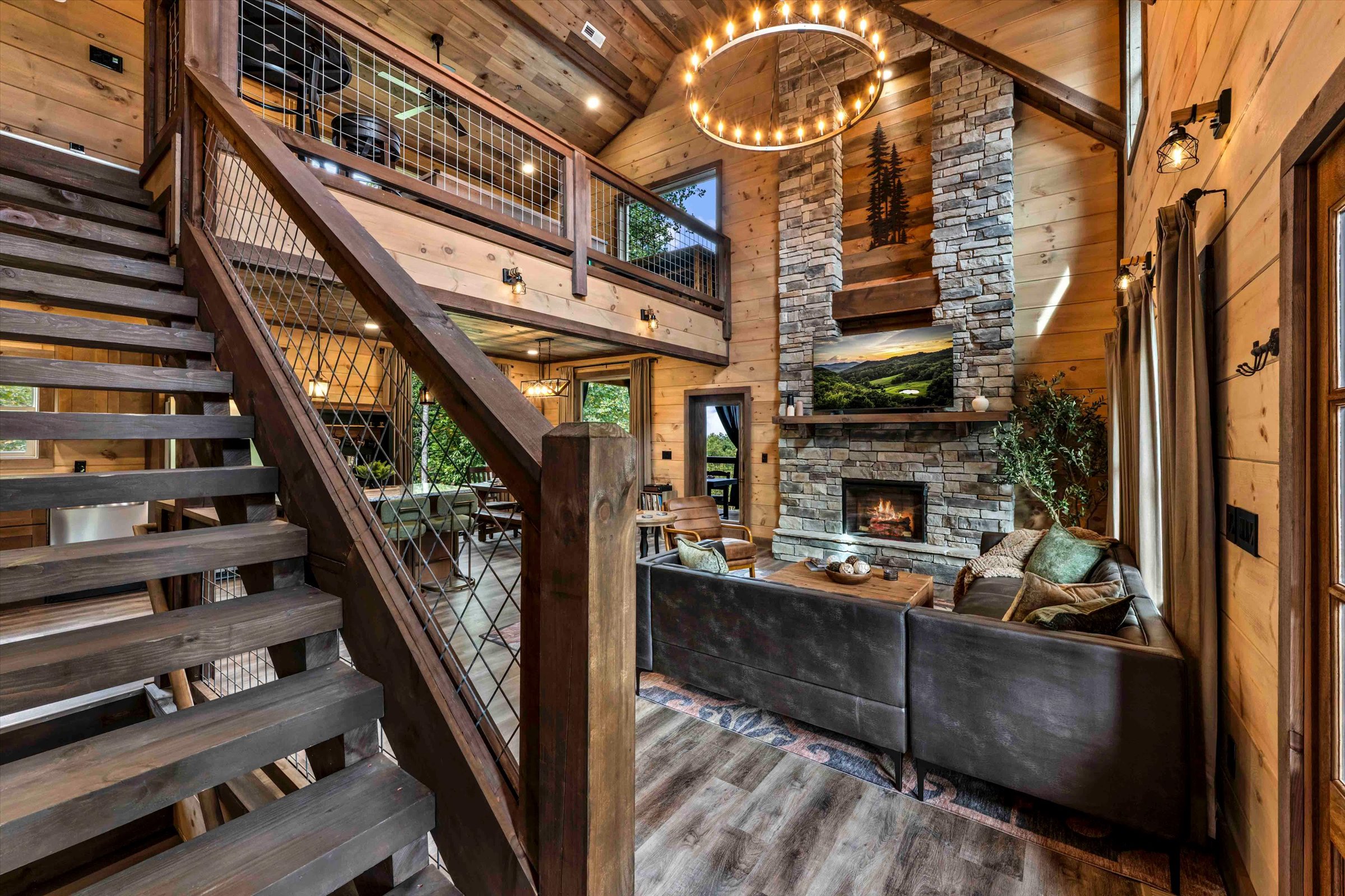 Soaring lodge-style living room with stone fireplace and loft