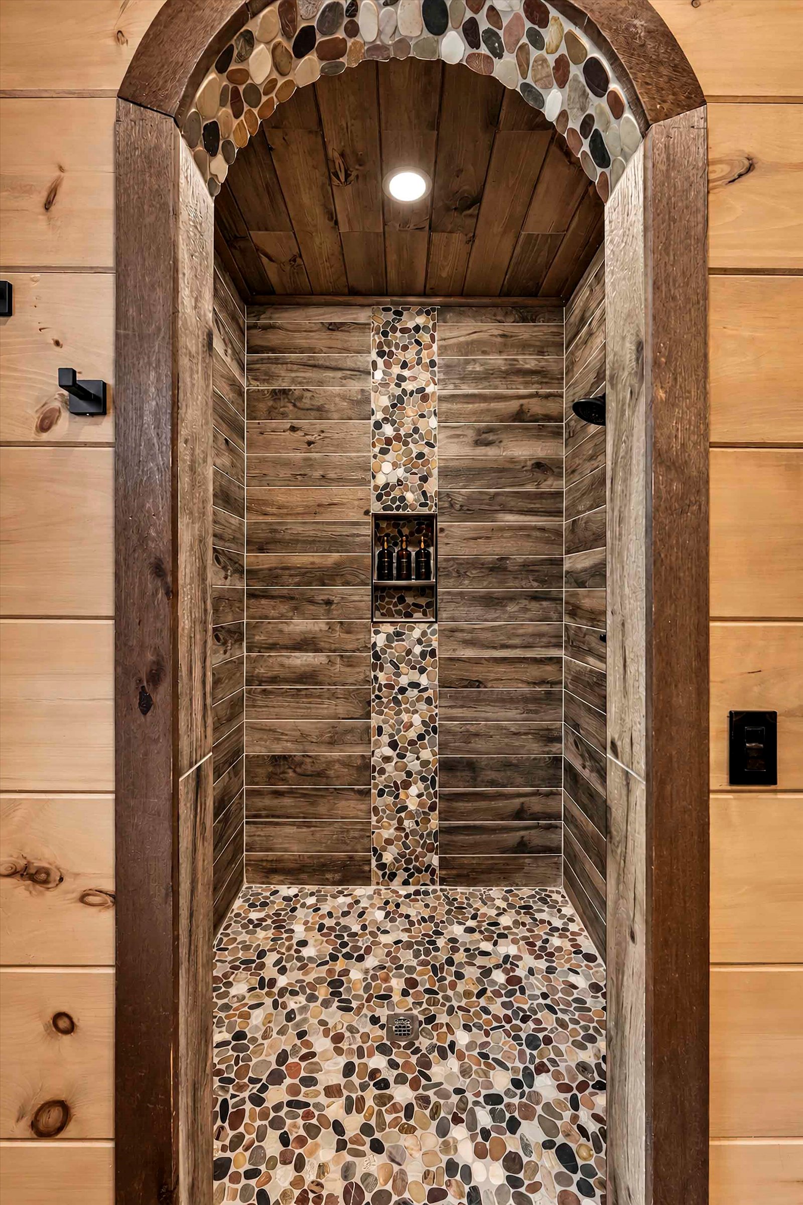 Rustic spa-style walk-in shower with pebble stone flooring