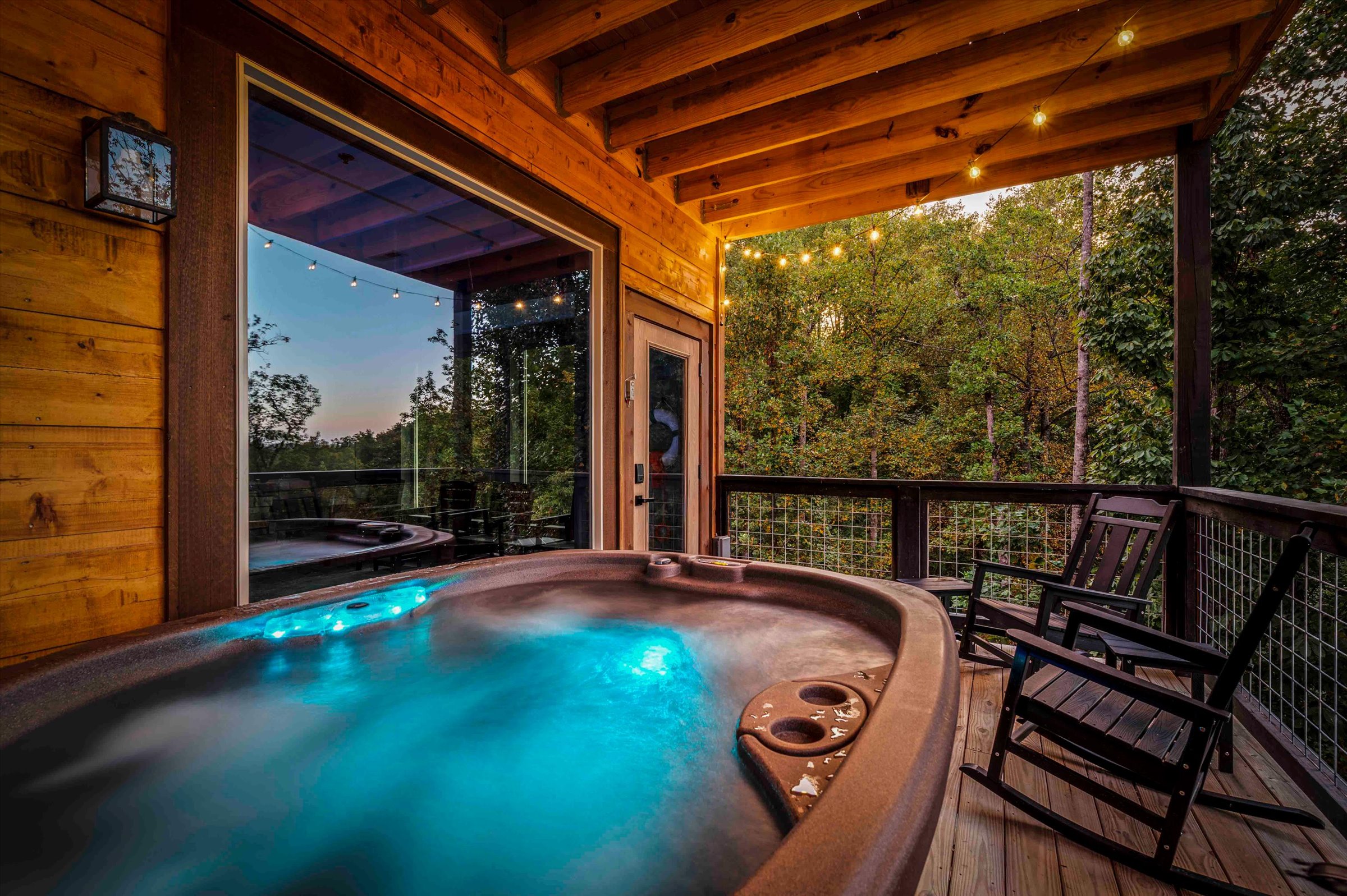 Private hot tub deck with forest views and cozy string lights