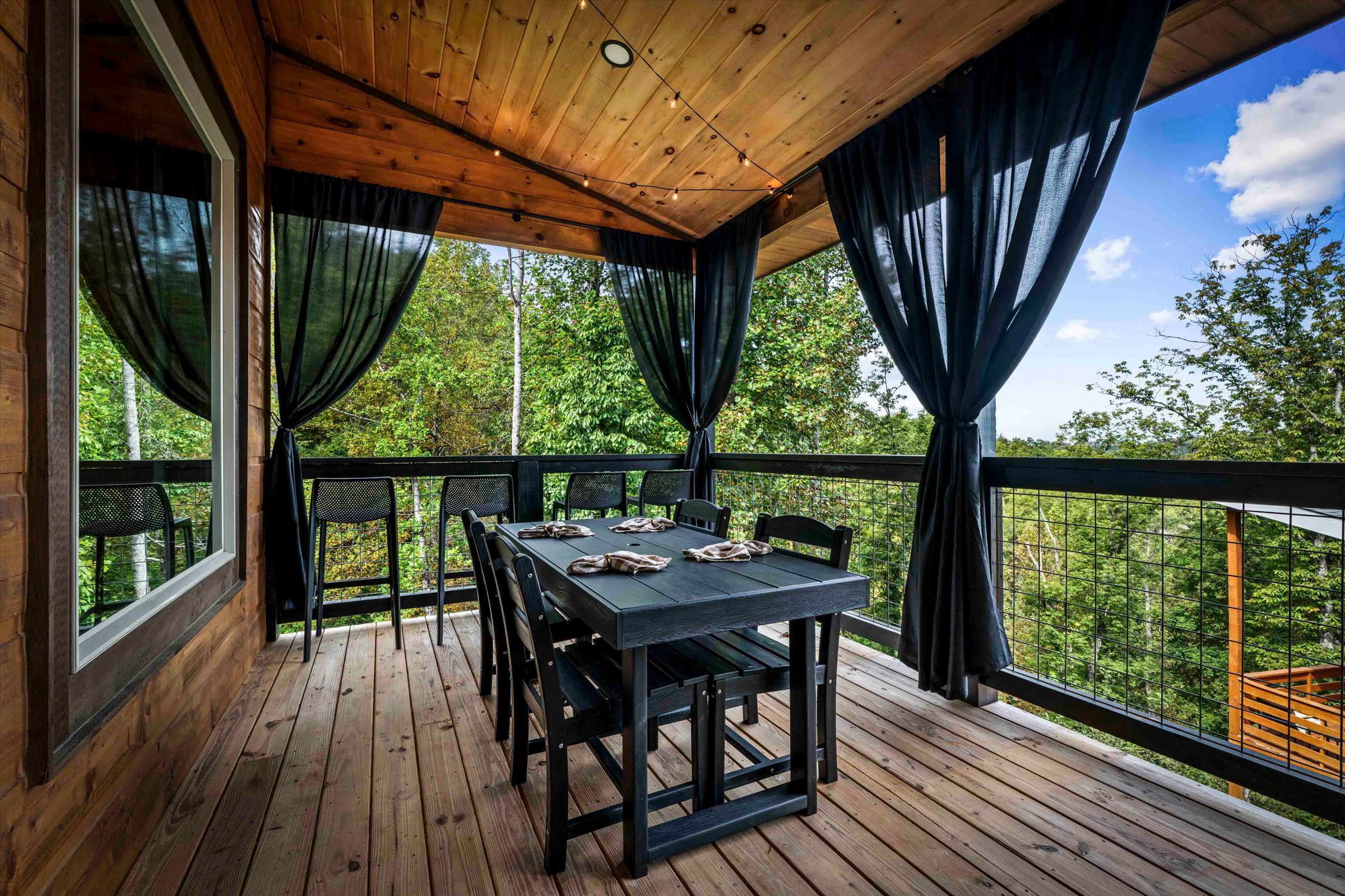 Covered treetop dining deck with stylish curtains and seating for six