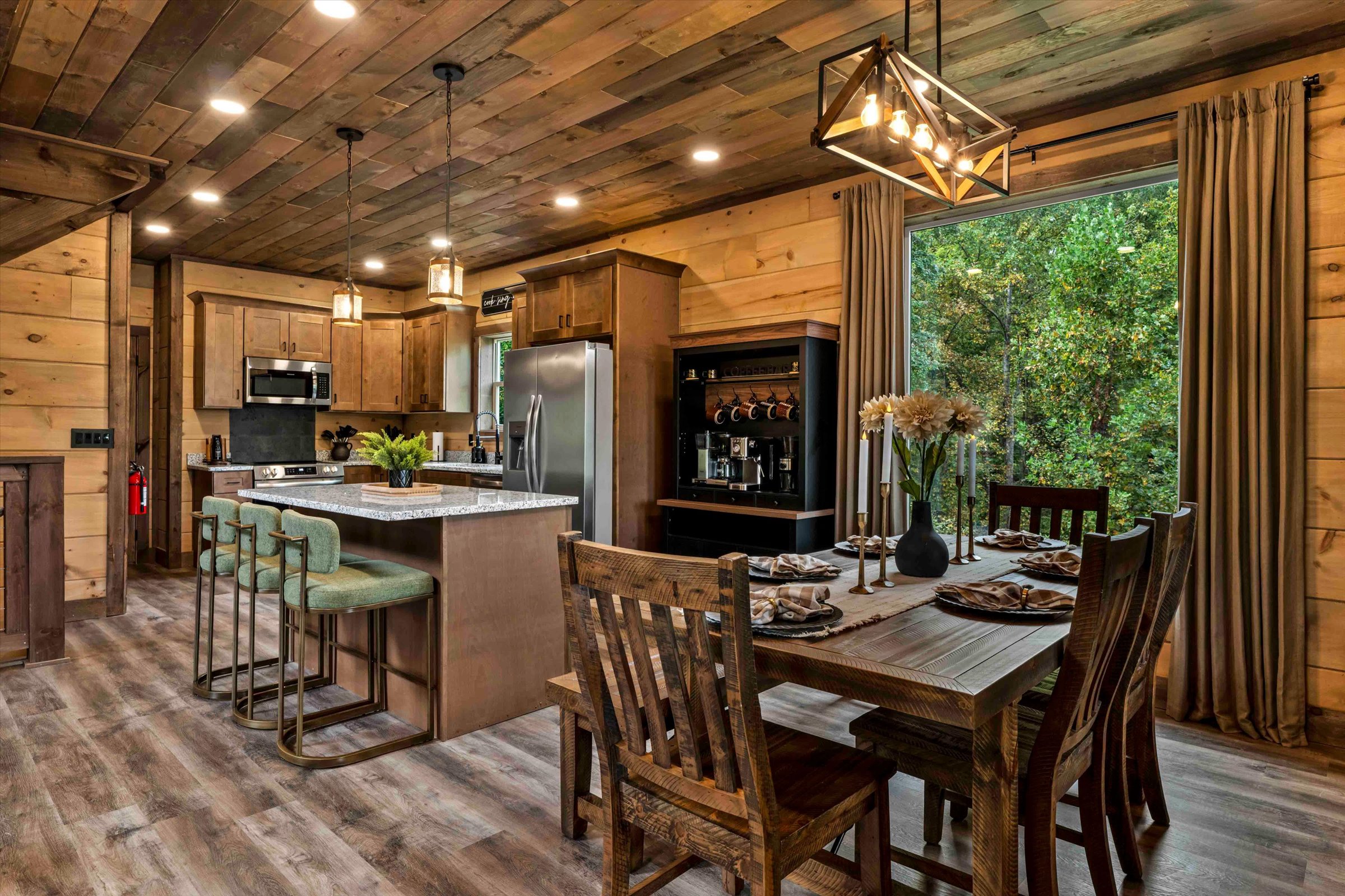 Rustic wood-clad kitchen and dining area with island seating and forest views