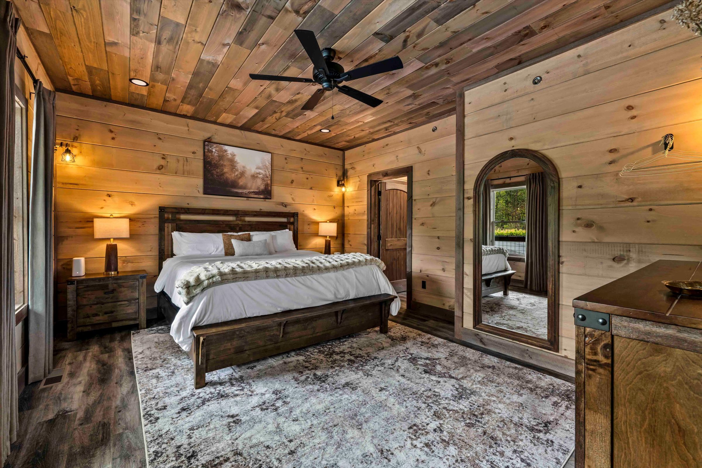 Cozy rustic king bedroom with wood finishes, soft lighting, and cabin charm