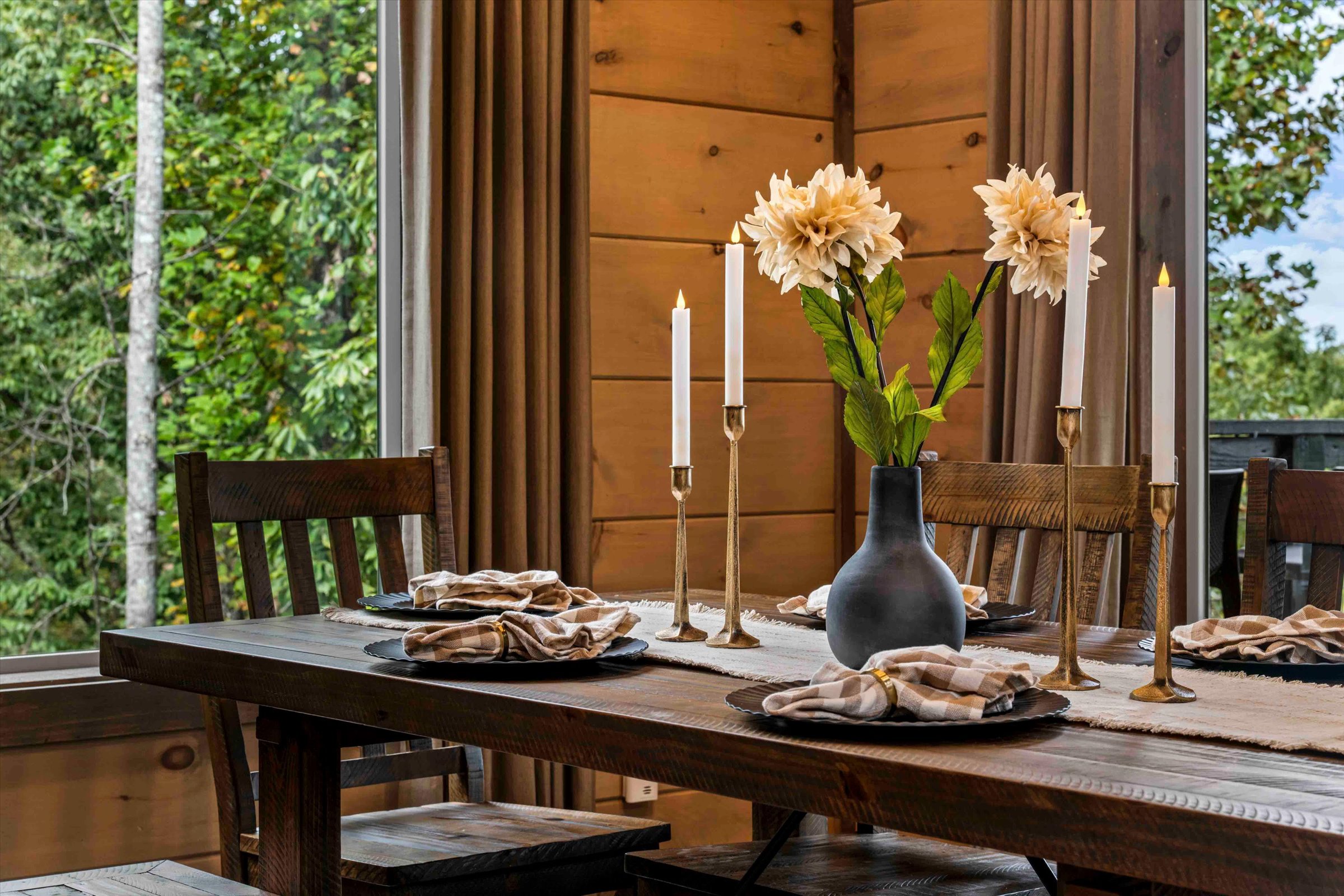 Rustic wood dining area with forest views and a cozy, candlelit table