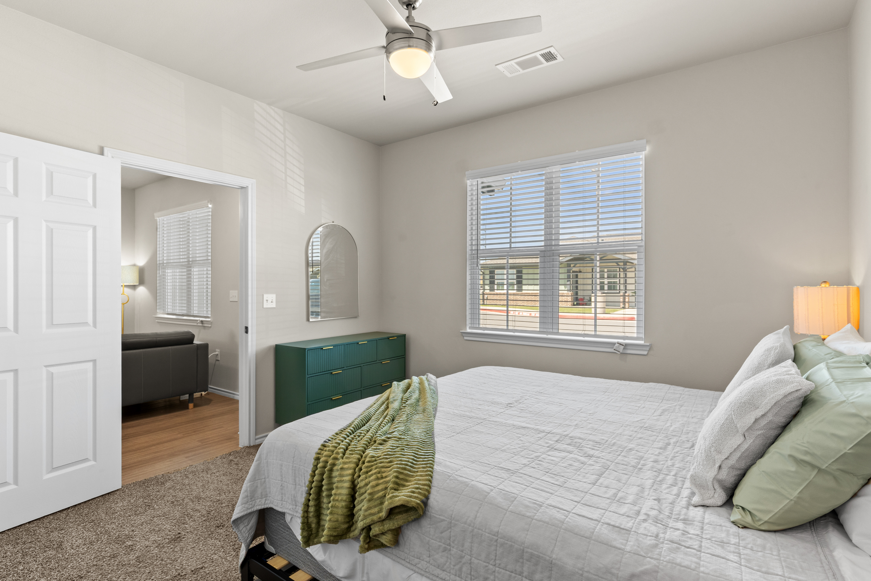 Bright, cozy bedroom with natural light, ceiling fan, and stylish accents