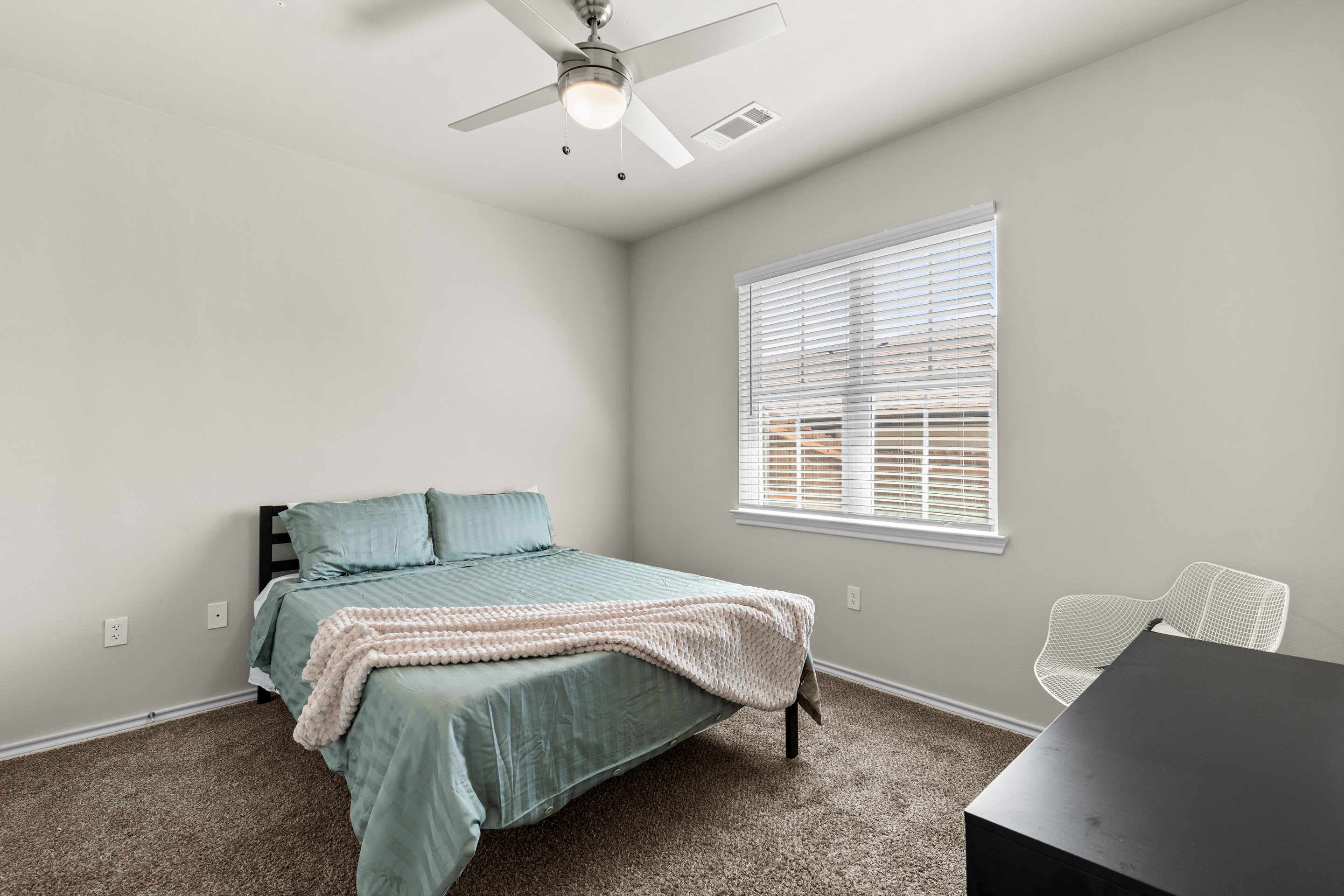 Bright, cozy bedroom with workspace, soft carpet, and natural light