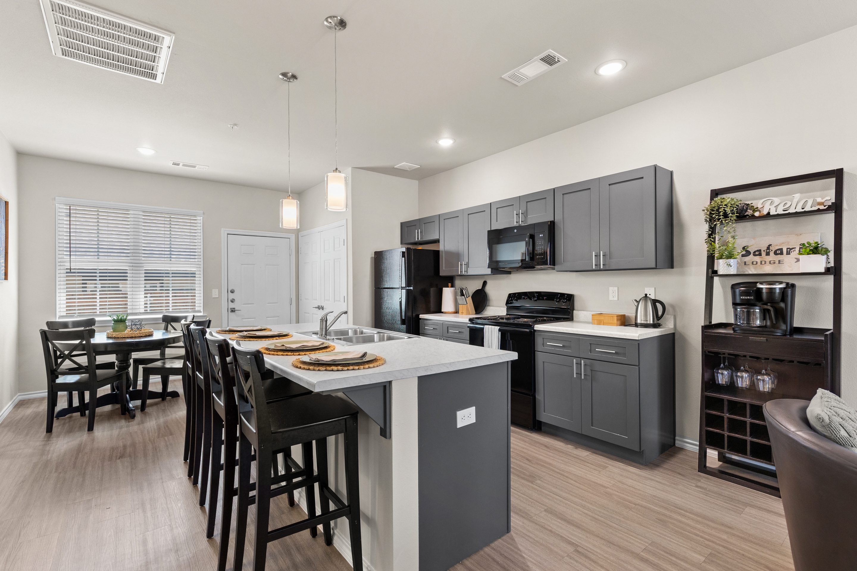 Modern open kitchen with island seating, dining nook, and handy coffee station