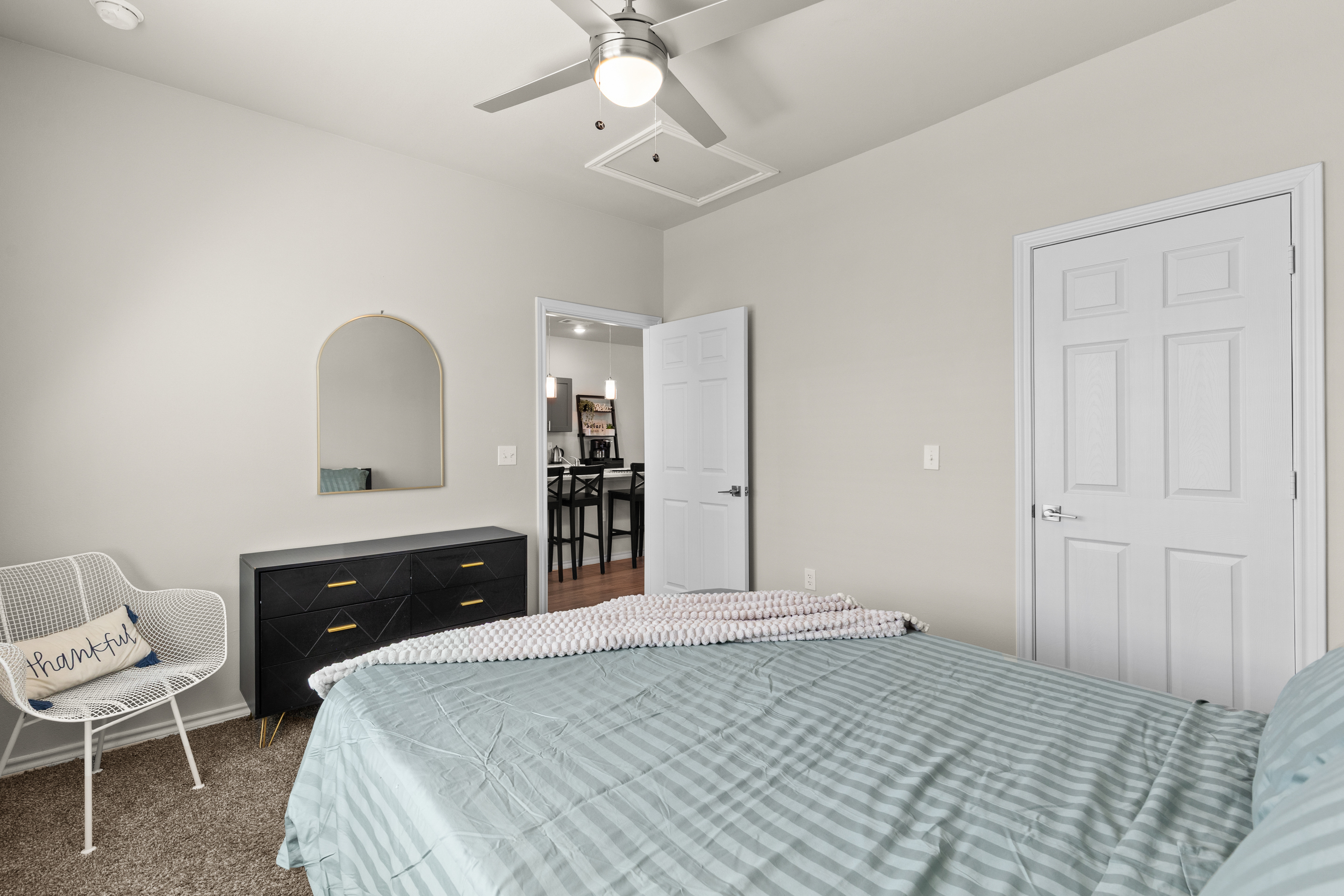 Bright, cozy bedroom with high ceilings, ceiling fan, and stylish decor