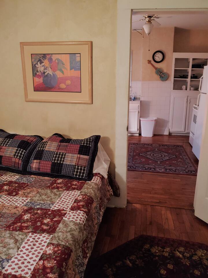 View from bedroom looking into kitchen. Each apartment has area rugs. As you can see, a different bed set was used the day this photo was taken as we like to decorate with an eclectic variety of quilts and shams.