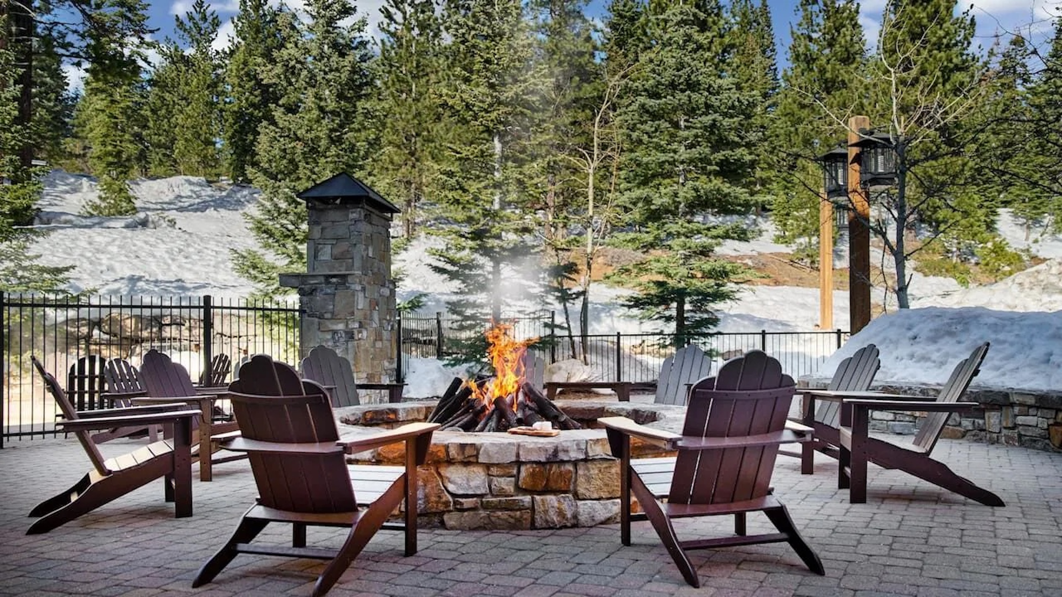 Cozy mountain fire pit patio surrounded by snow and towering pines