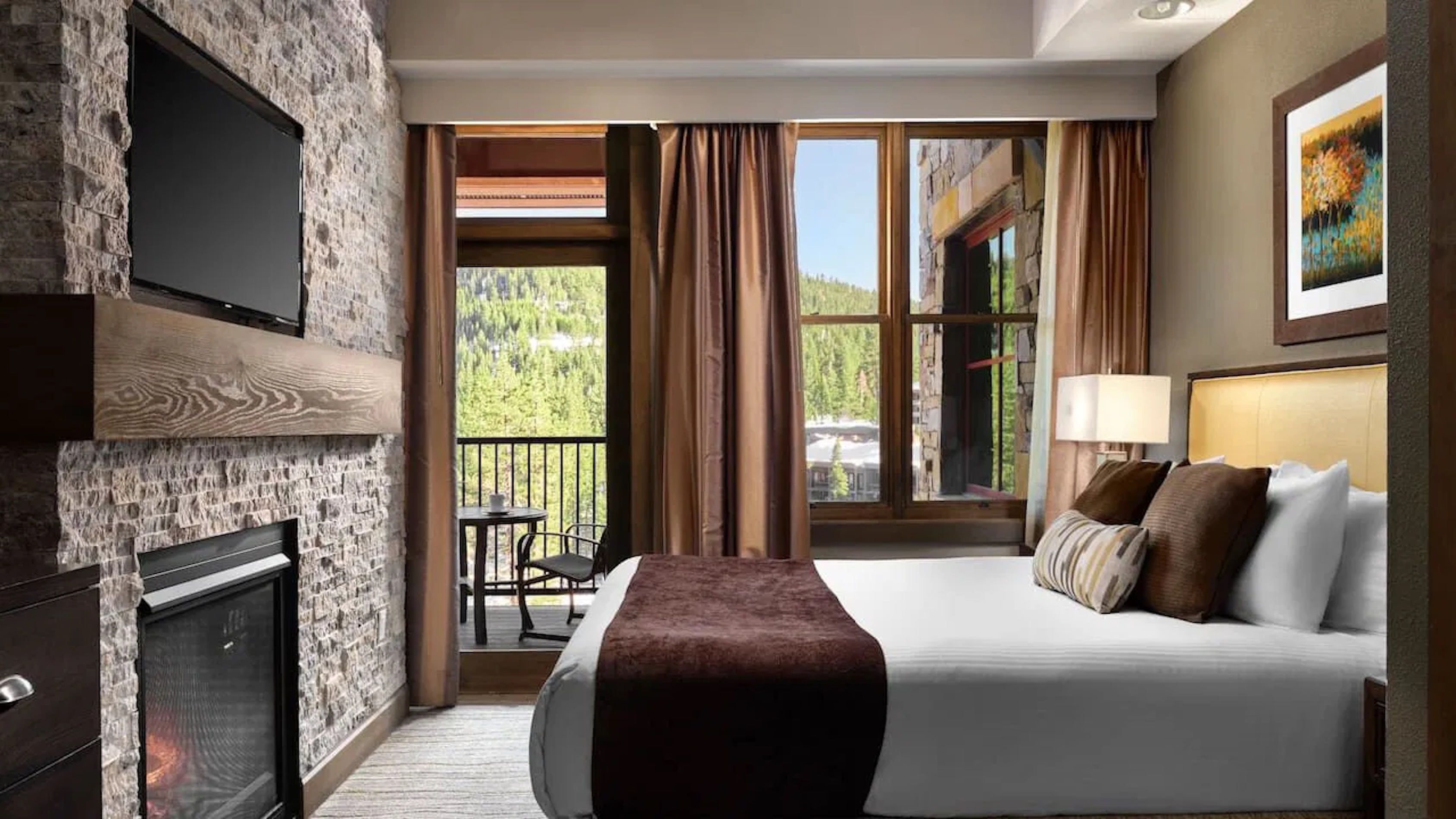 Cozy mountain-view bedroom with fireplace, TV, and private balcony