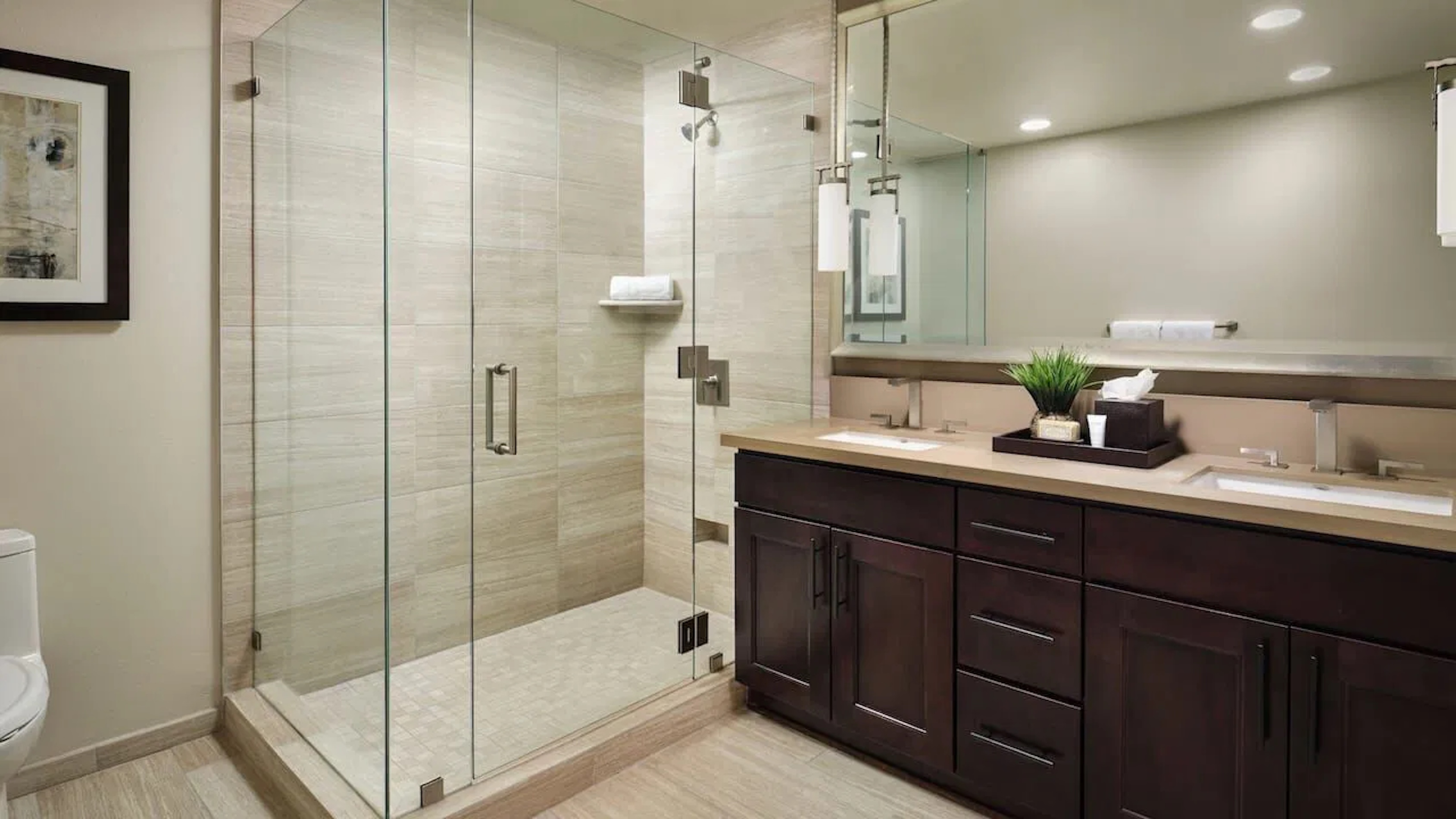 Spa-style bathroom with double vanity and oversized glass shower