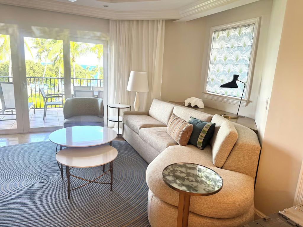 Bright tropical living room with balcony and water-view peek