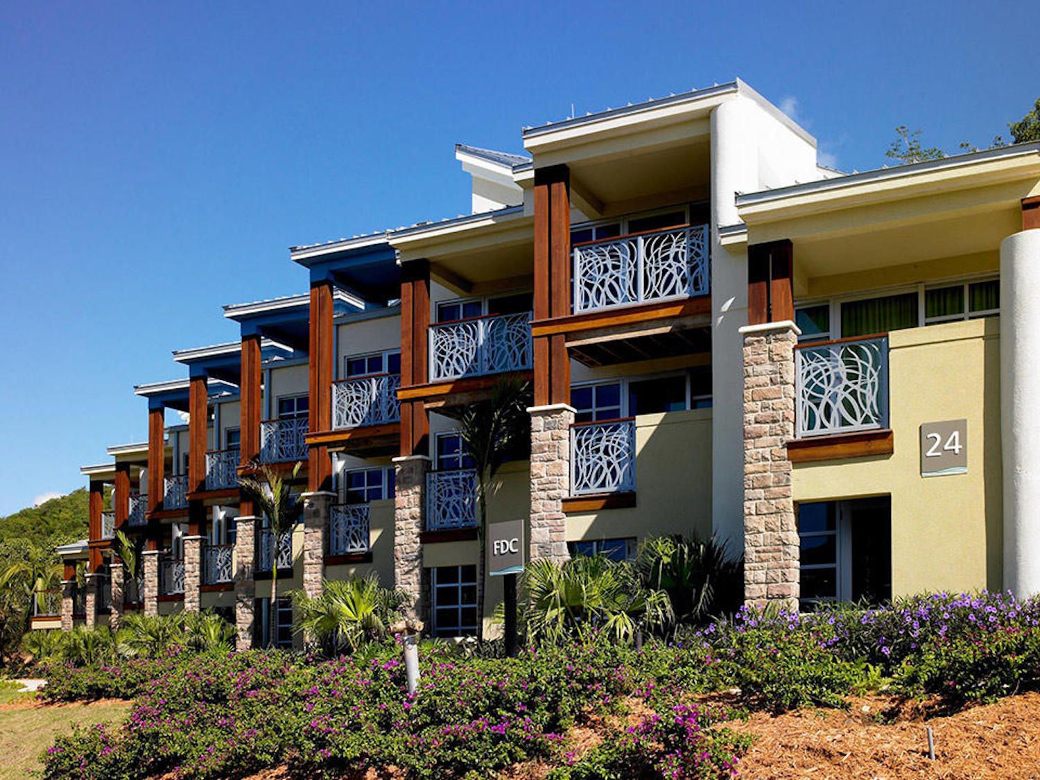 Modern resort-style building with private balconies and tropical landscaping