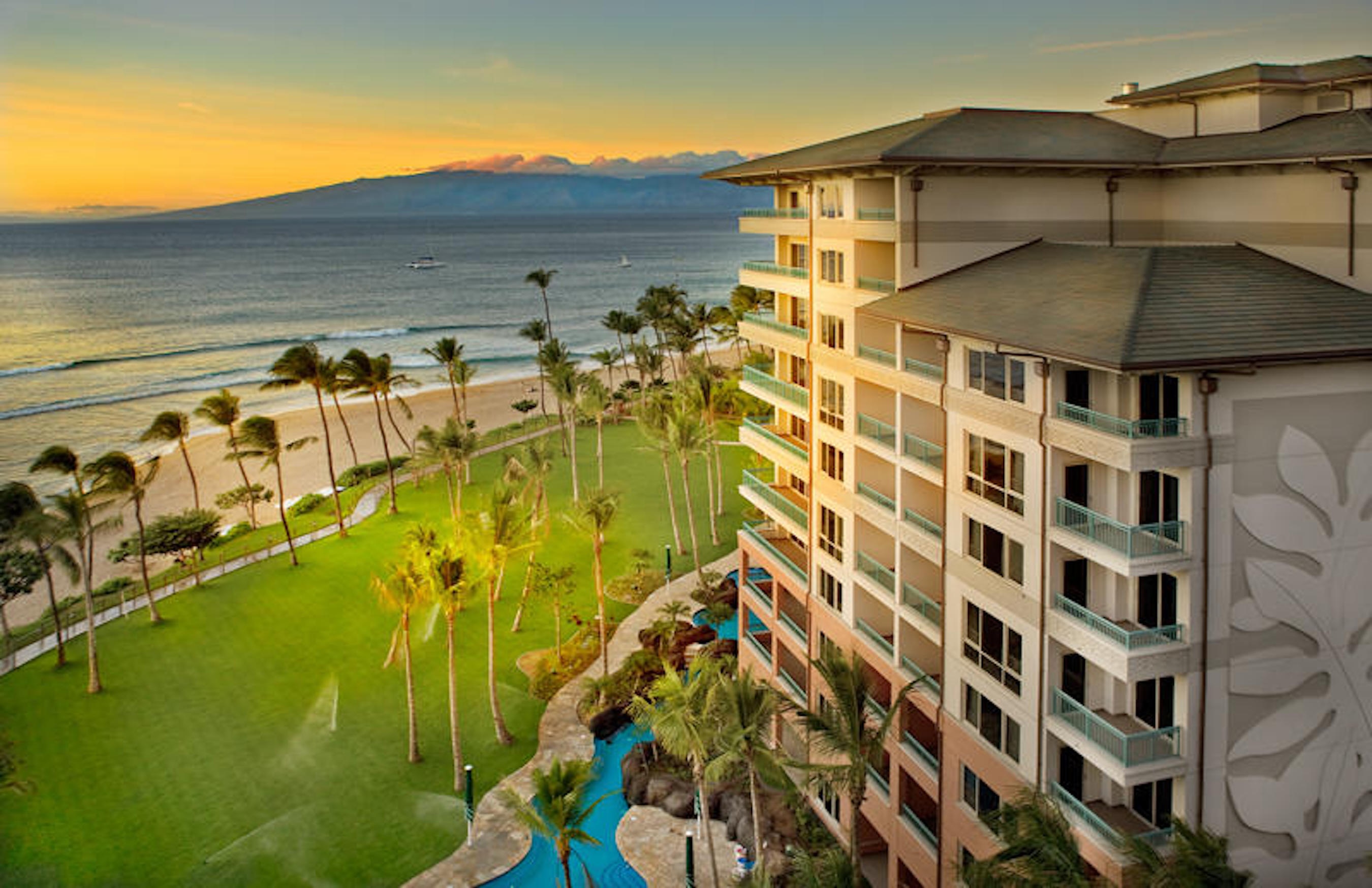 Beachfront resort views with palm-lined grounds, pool, and stunning sunset