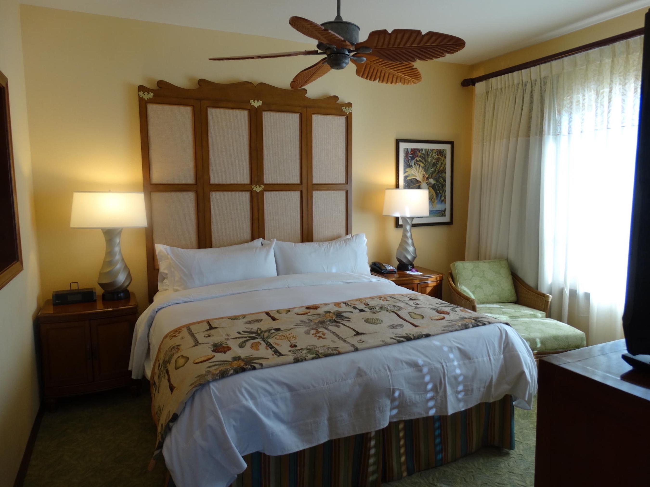 Cozy king bedroom with tropical charm, soft light, and lounge seating