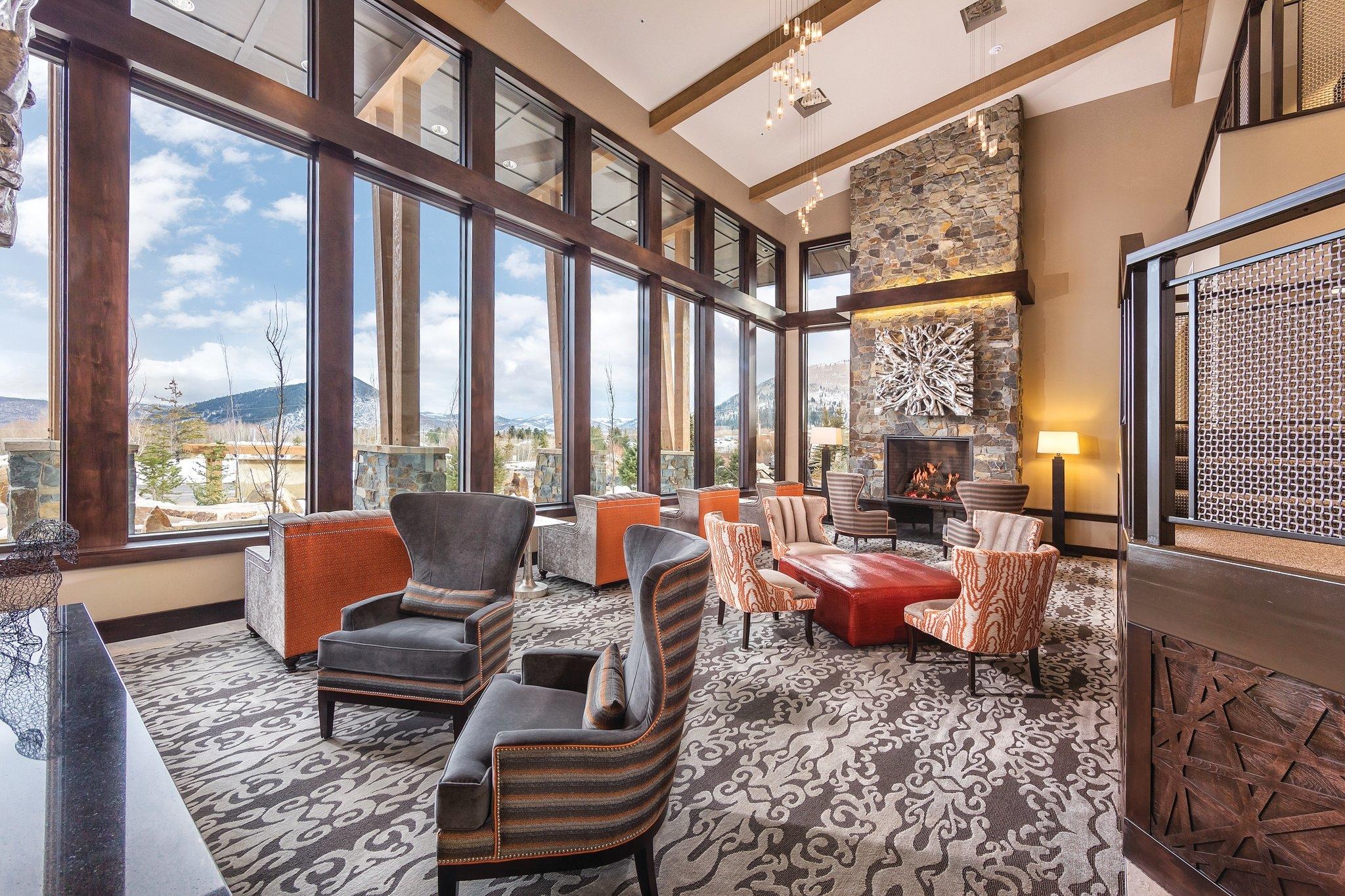 Bright mountain-view lounge with soaring windows and a cozy stone fireplace