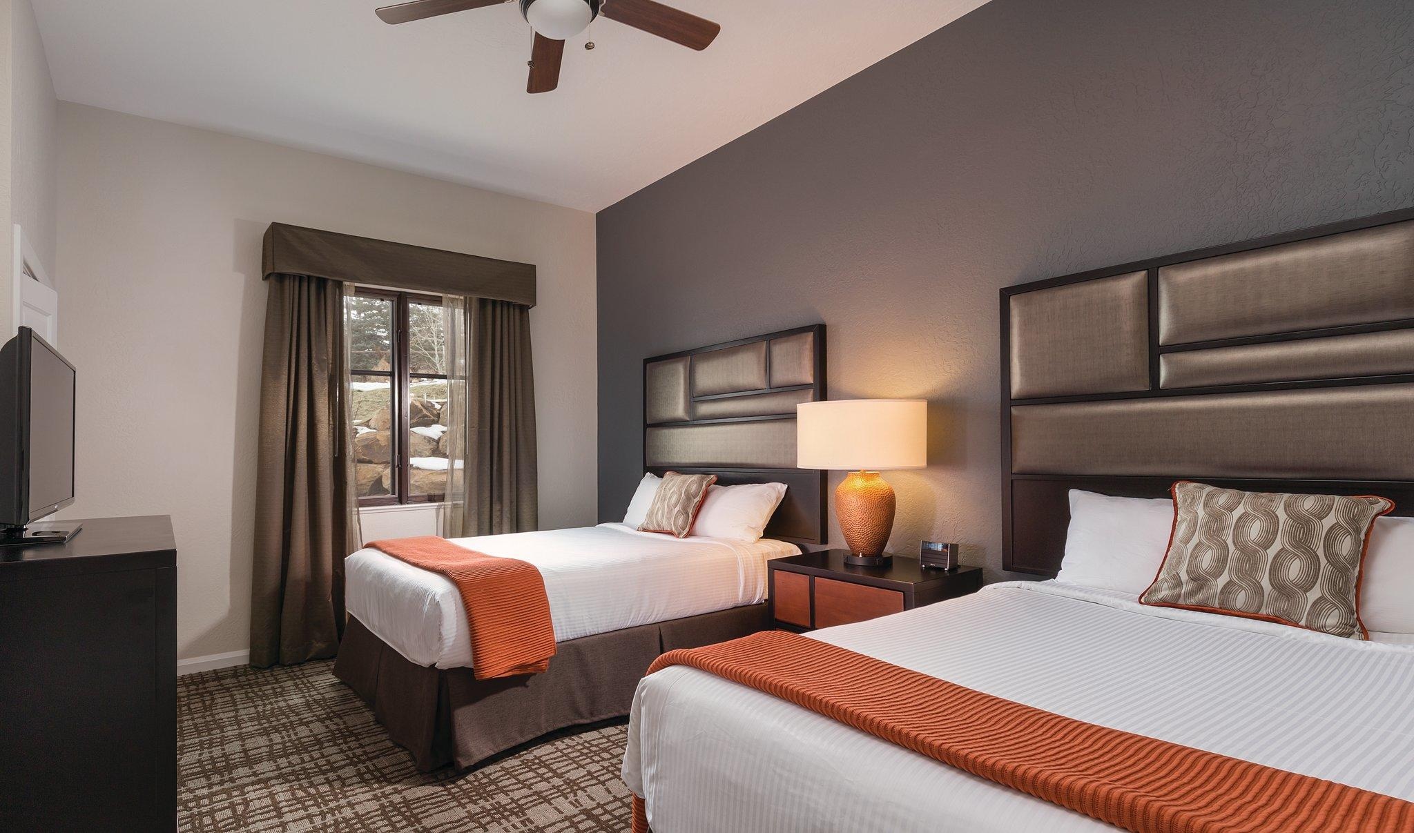 Modern double-queen room with stylish décor, TV, and cozy lighting