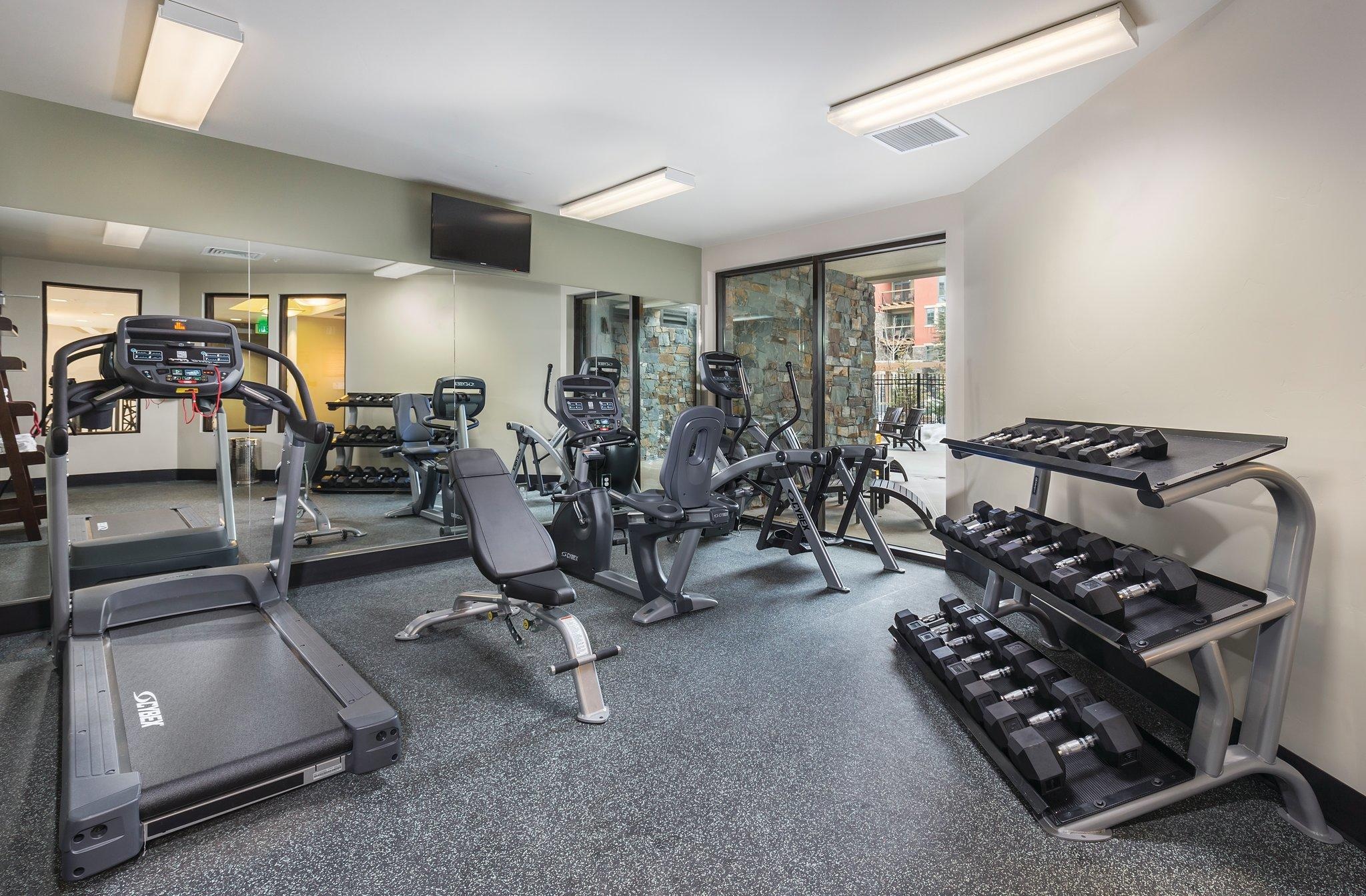 Bright on-site fitness room with cardio machines and free weights