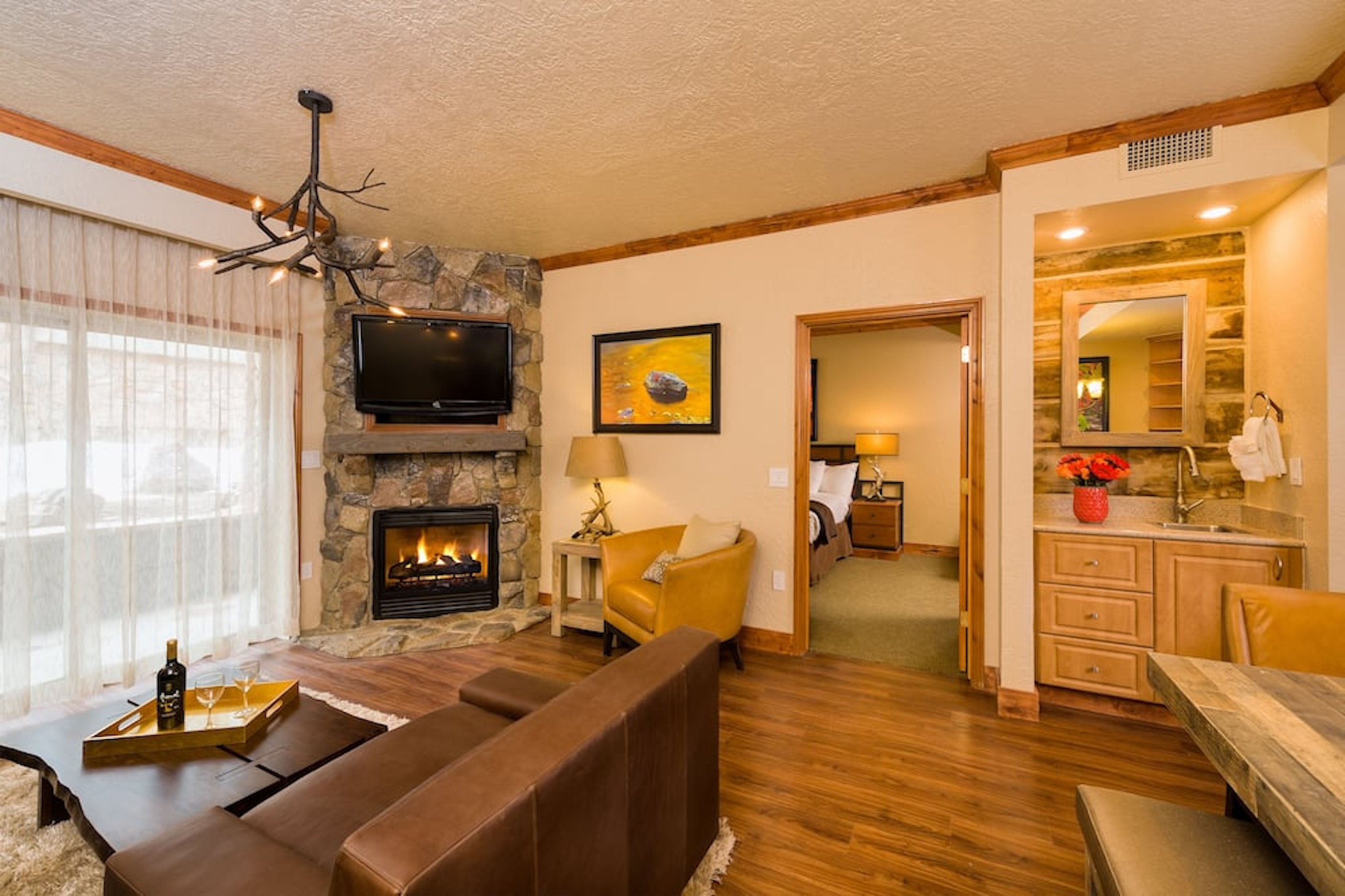 Cozy lodge-style suite with stone fireplace, TV, and rustic mountain charm