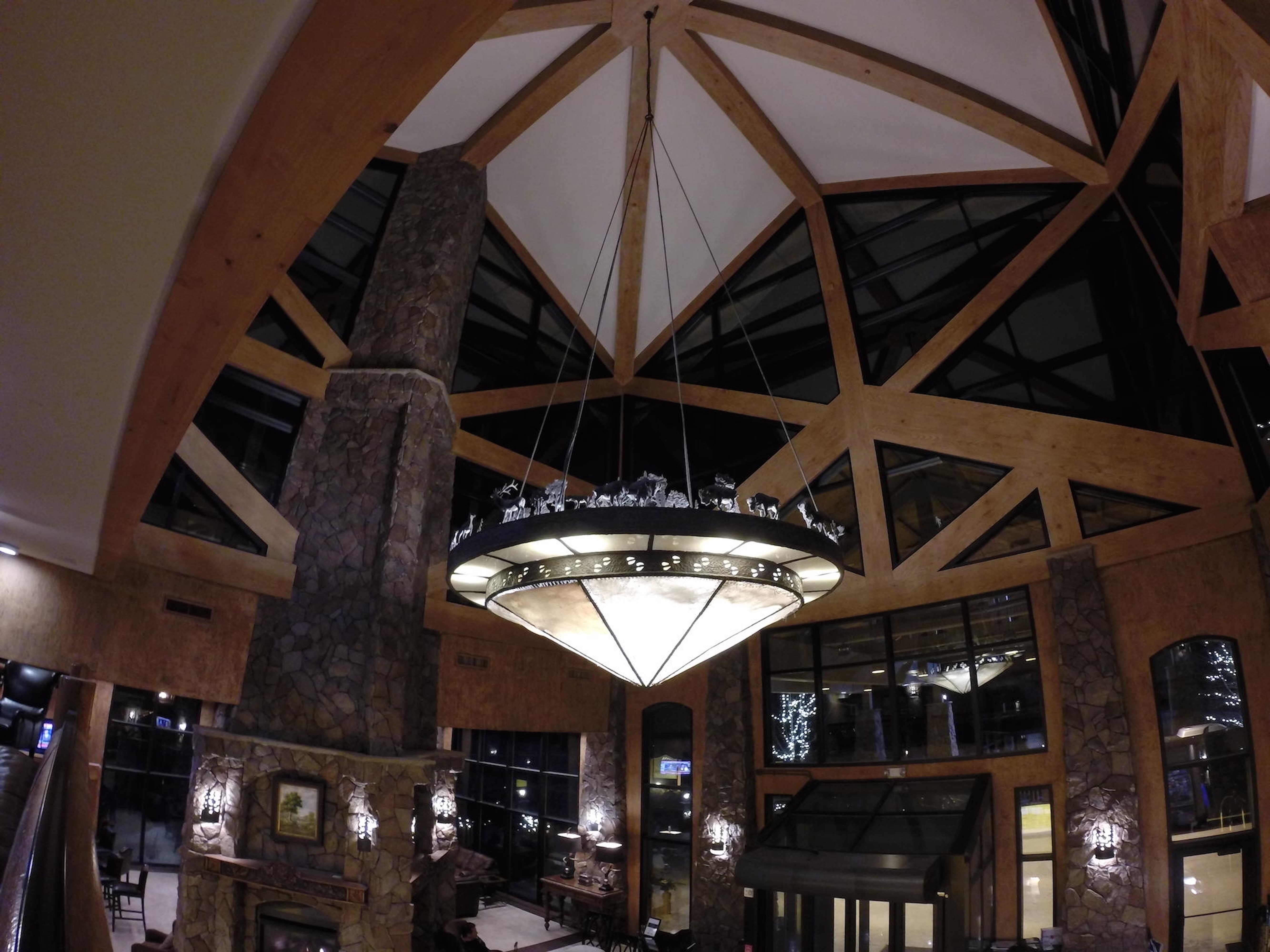 Grand lodge-style great room with soaring beams, stone fireplace & chandelier