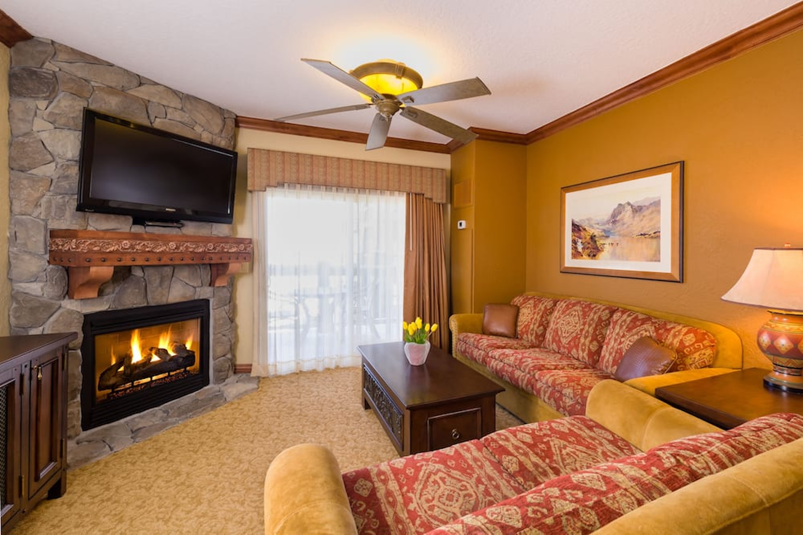 Cozy lodge-style living room with stone fireplace and large sunny window