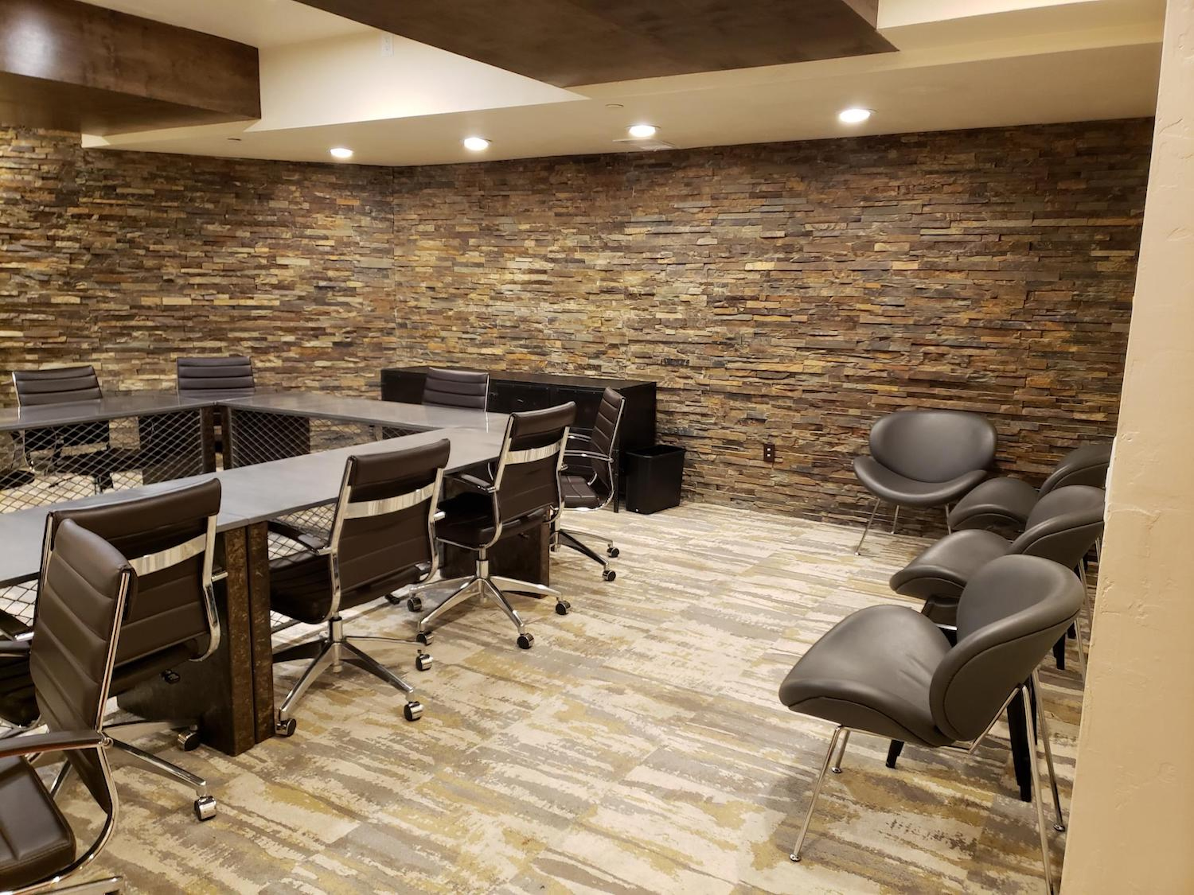 Modern meeting lounge with coworking tables and stylish stone accent wall