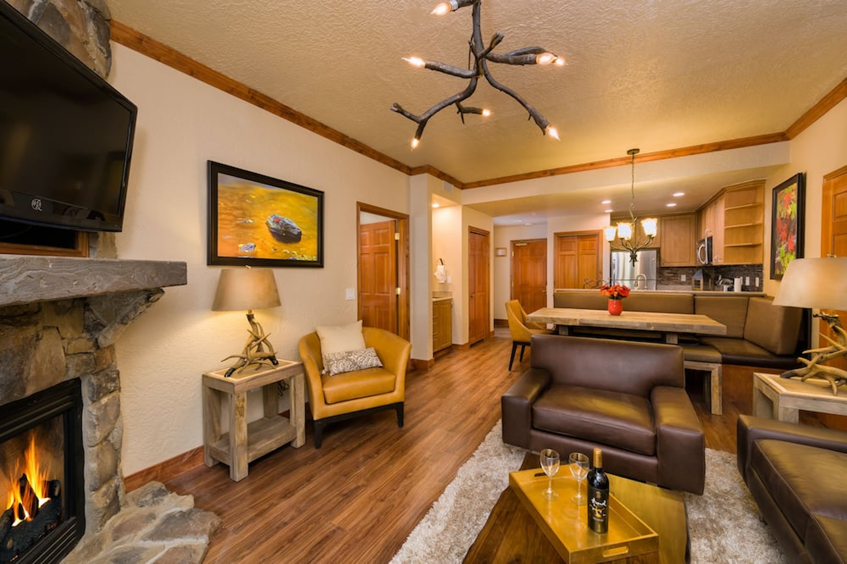 Cozy lodge-style living room with fireplace, dining nook, and full kitchen
