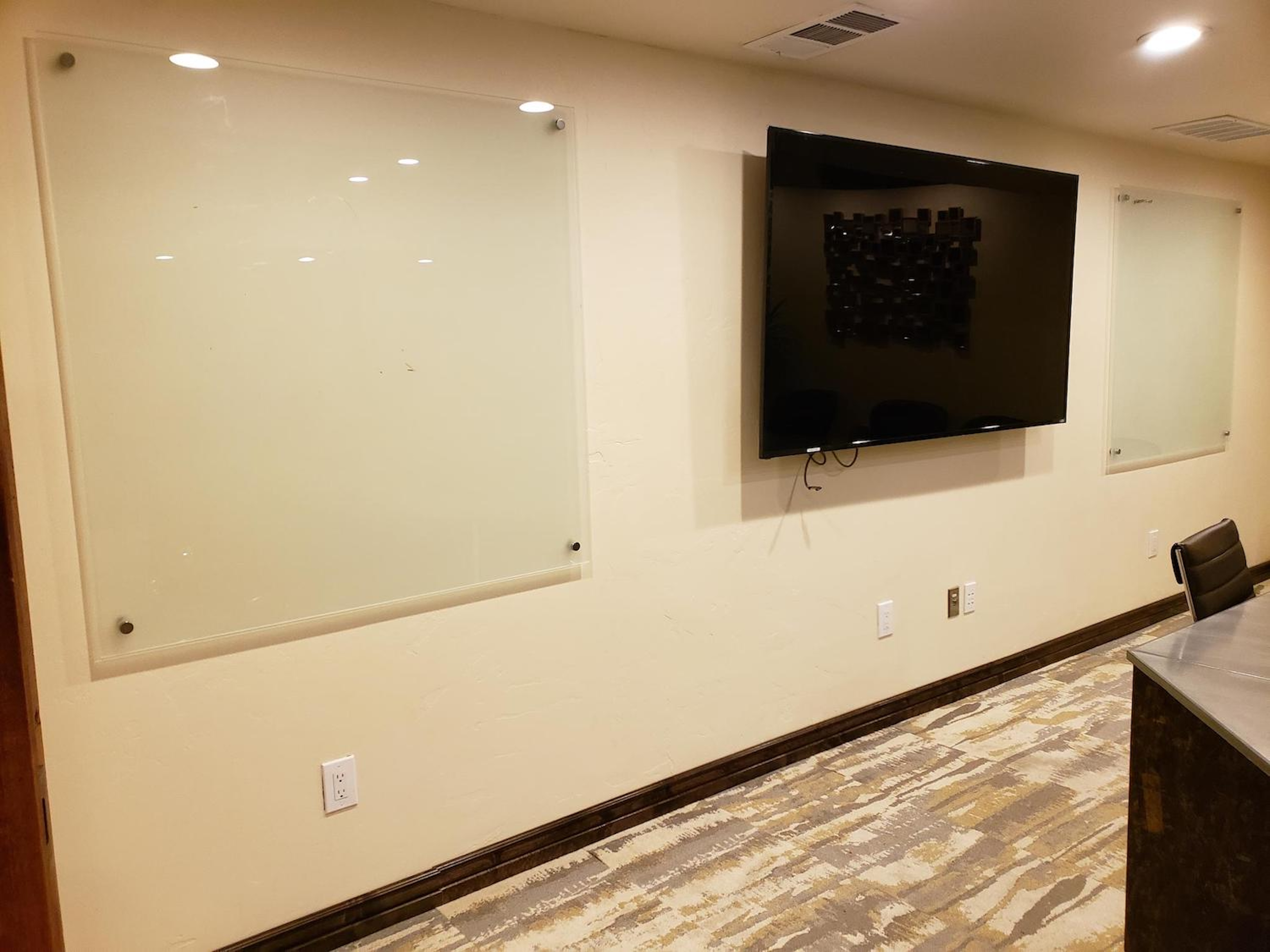 Modern meeting room with large TV and glass whiteboards