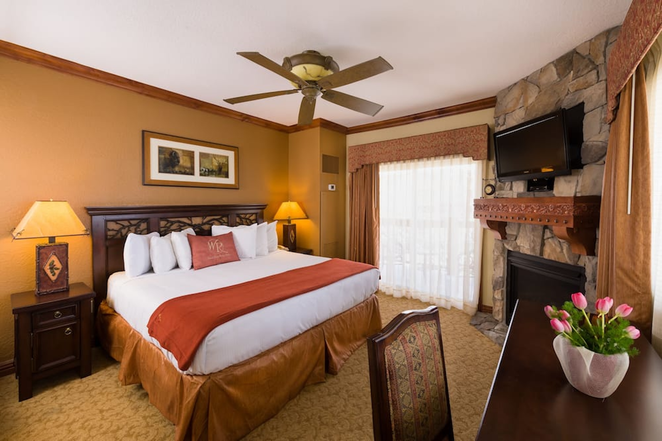 Cozy lodge-style king room with fireplace, TV, and warm rustic charm