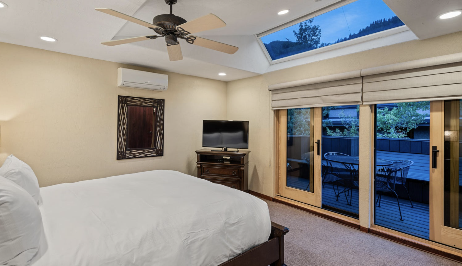 Bright bedroom with skylight, private deck access, and cozy modern comforts