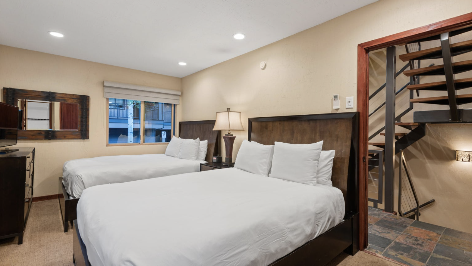 Spacious two-queen bedroom with warm finishes and easy loft/stair access