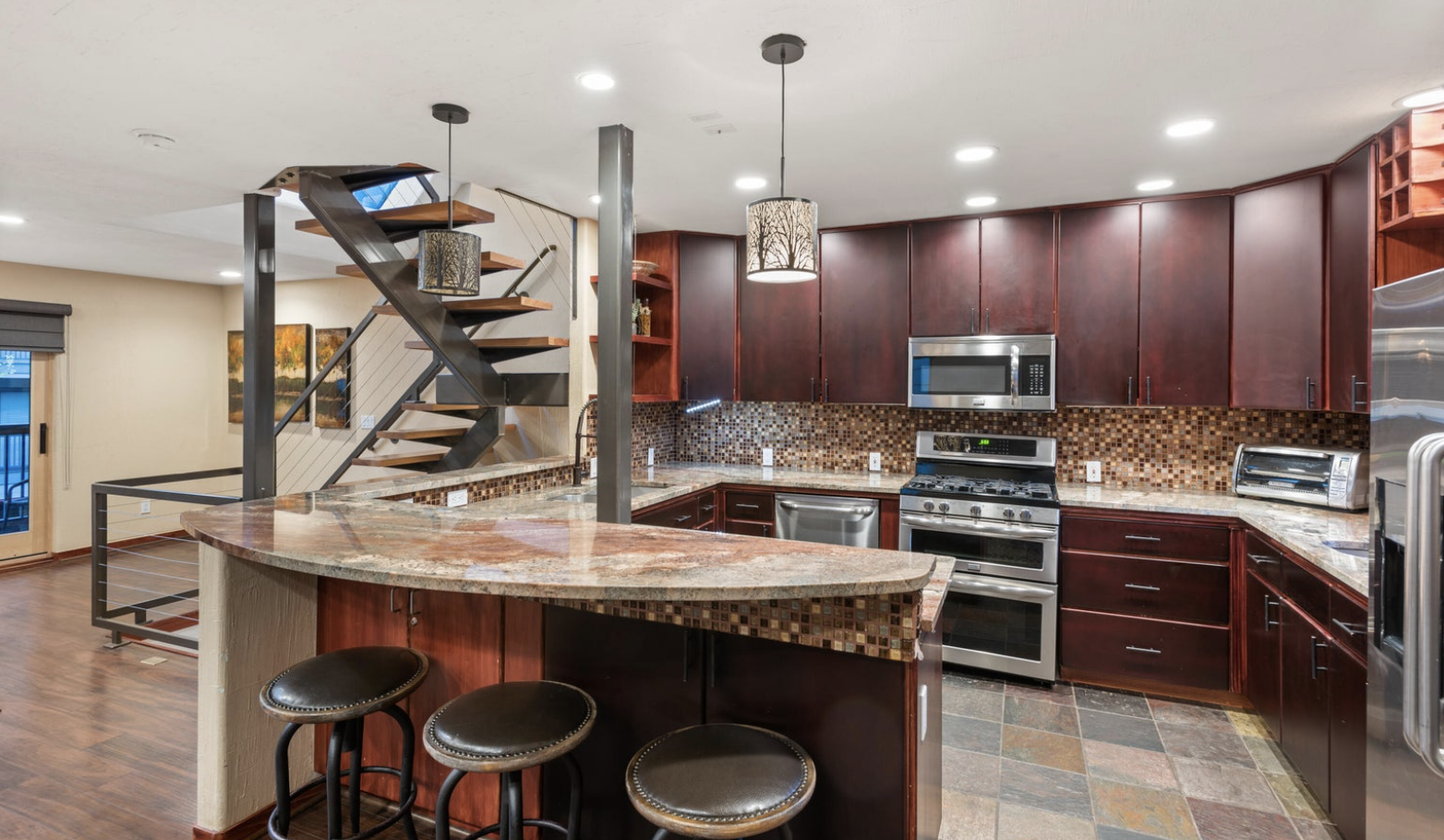 Modern gourmet kitchen with breakfast bar and striking open staircase