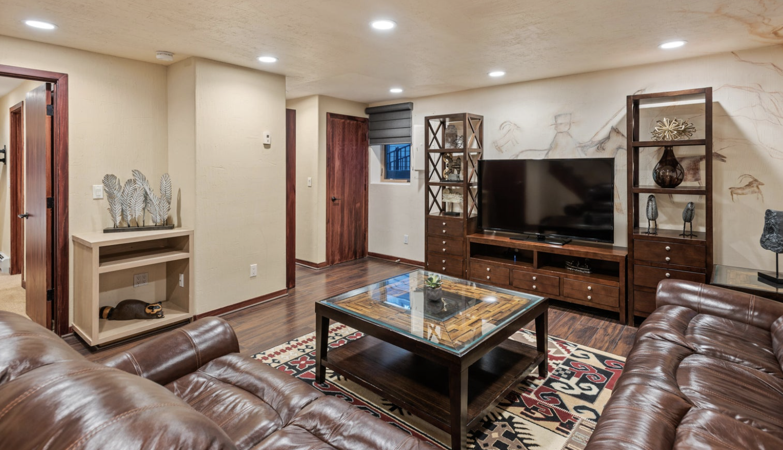 Cozy lounge with leather seating, large TV, and warm modern style