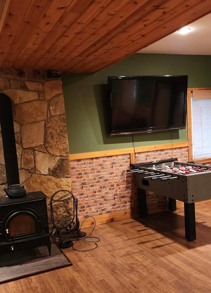 Cozy game room with foosball, big-screen TV, and rustic wood stove