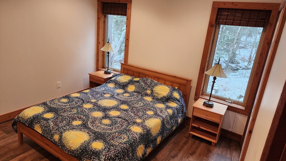 Cozy woodland bedroom with large windows and warm rustic touches