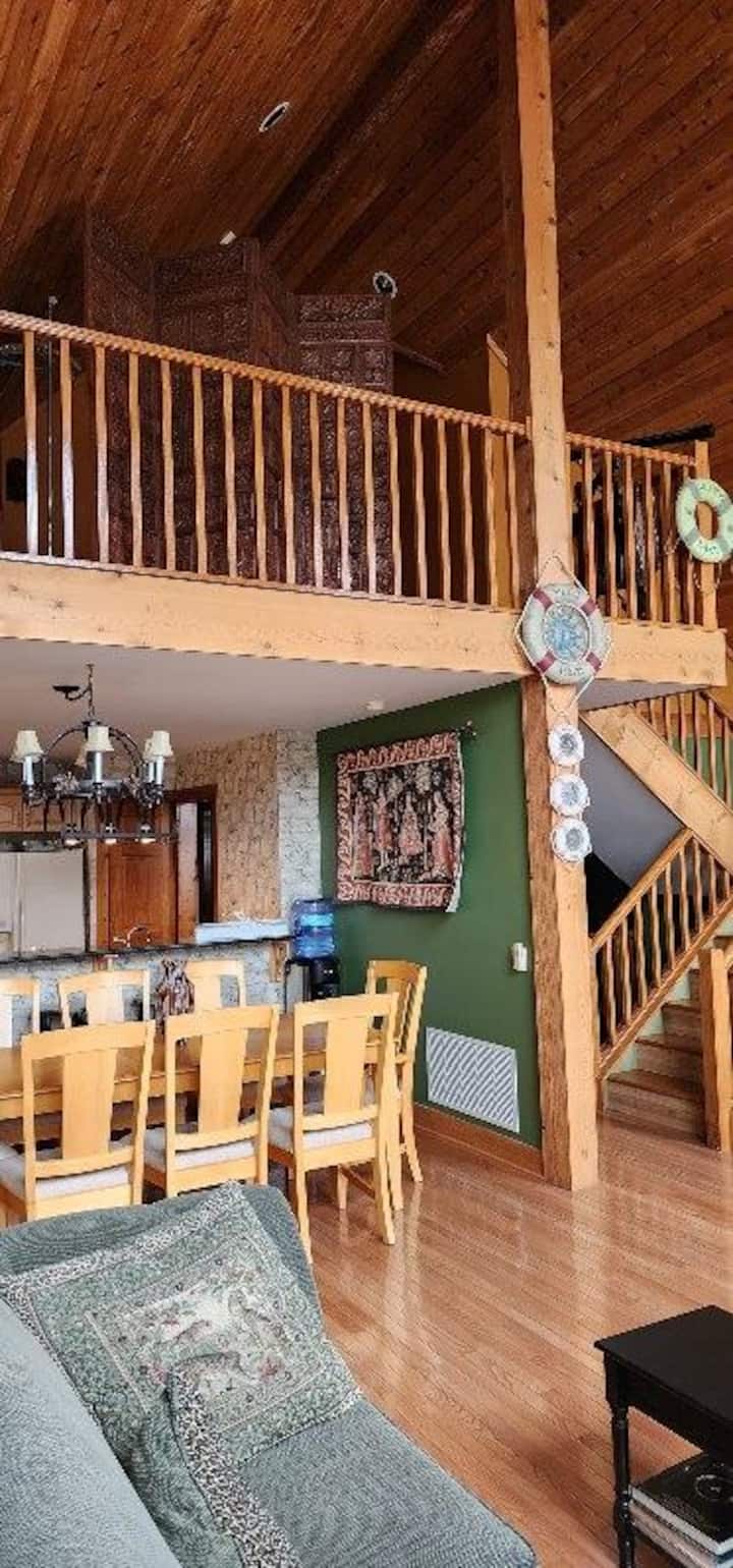Rustic great room with loft, vaulted wood ceilings, and spacious dining area