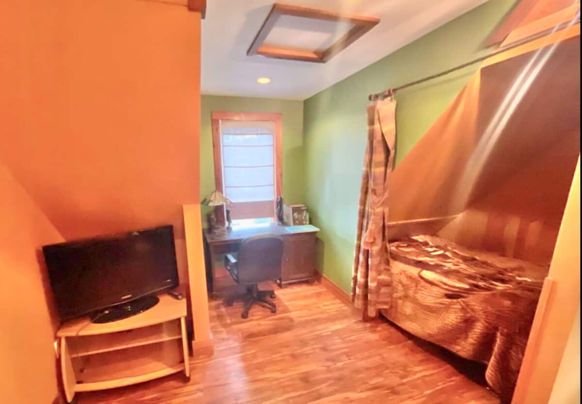 Cozy alcove bedroom with desk, TV, and warm colorful design