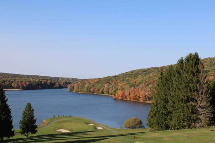 Scenic lakefront golf views framed by vibrant autumn hills