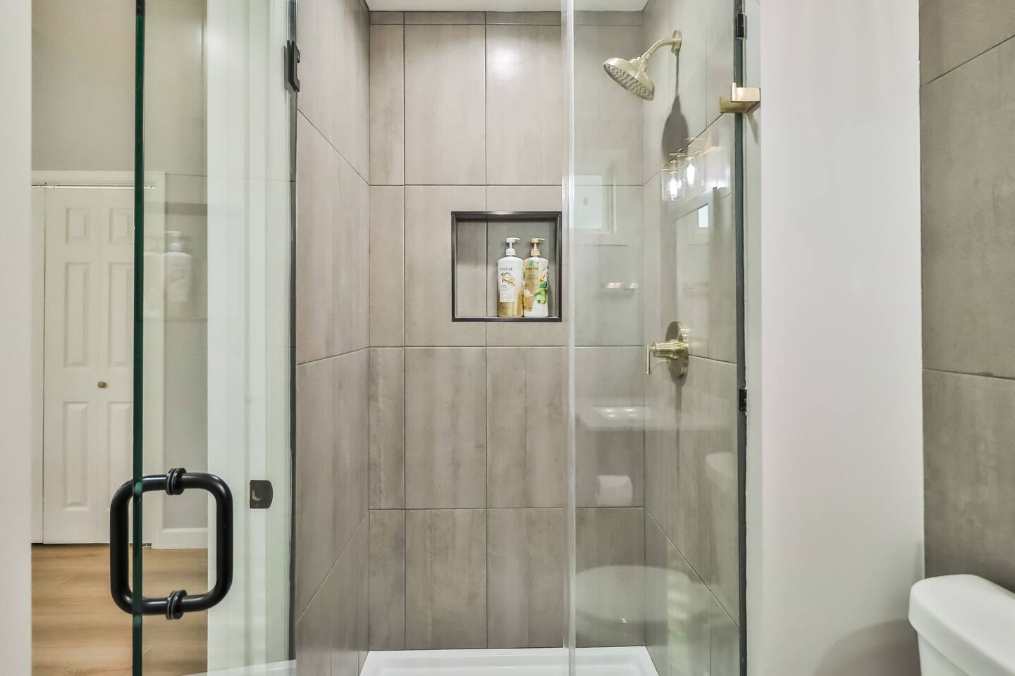 Modern bathroom renovation featuring a navy blue vanity, white granite countertop, brushed gold faucet, and matching gold towel hardware.