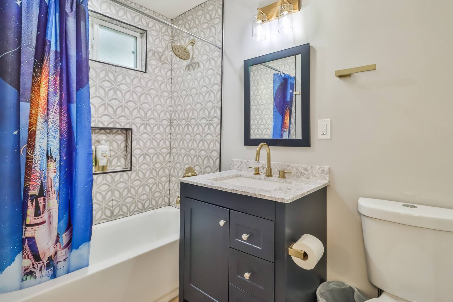 Modern bathroom renovation featuring a navy blue vanity, white granite countertop, brushed gold faucet, and matching gold towel hardware.