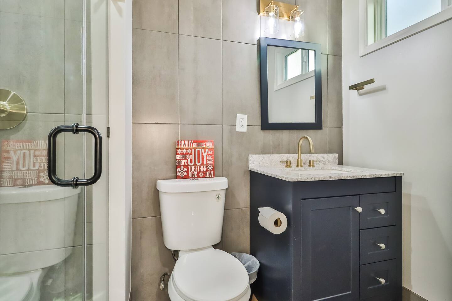 Modern bathroom renovation featuring a navy blue vanity, white granite countertop, brushed gold faucet, and matching gold towel hardware.