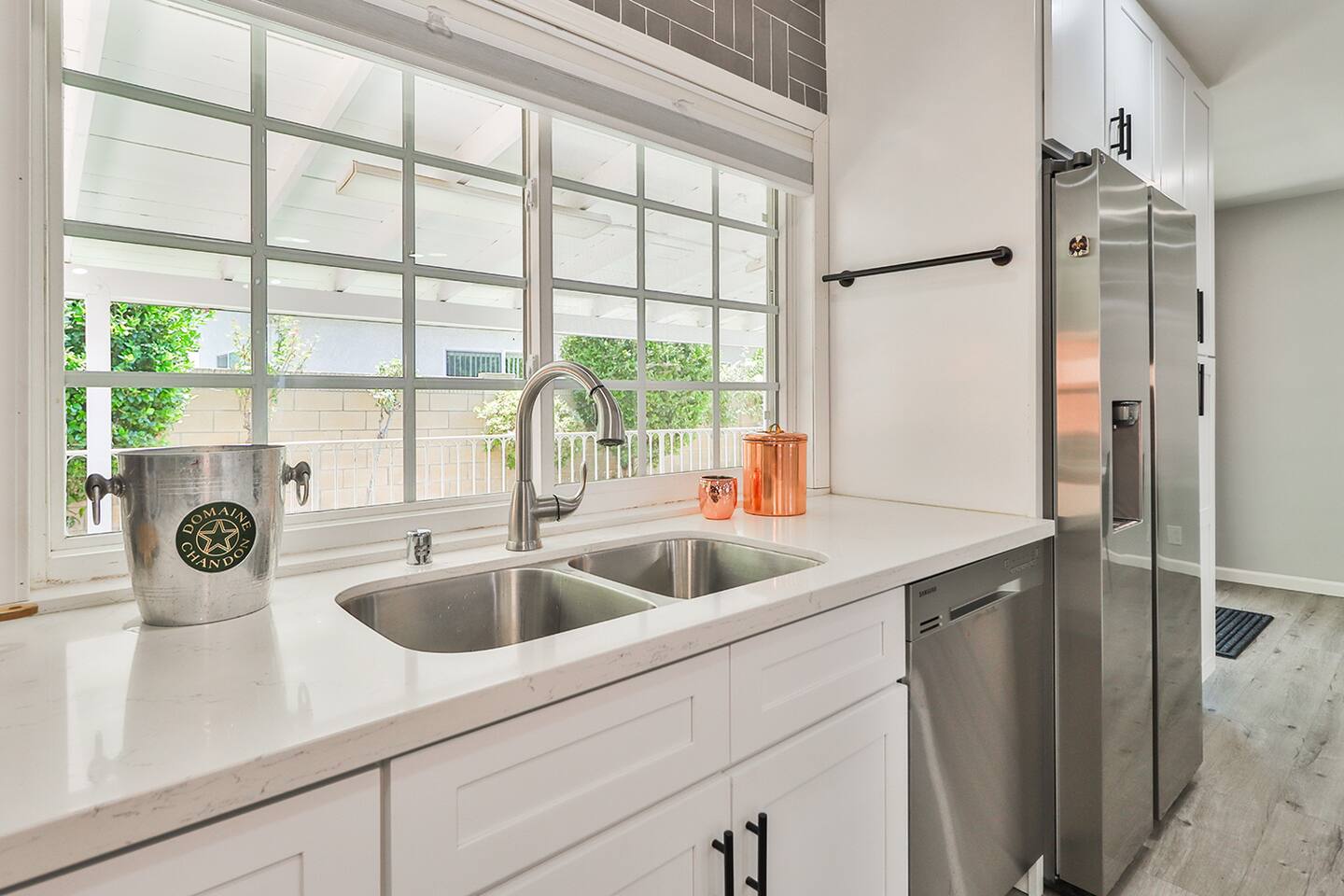 Bathed in natural light from a large window, the bright kitchen sink area, with its double basin