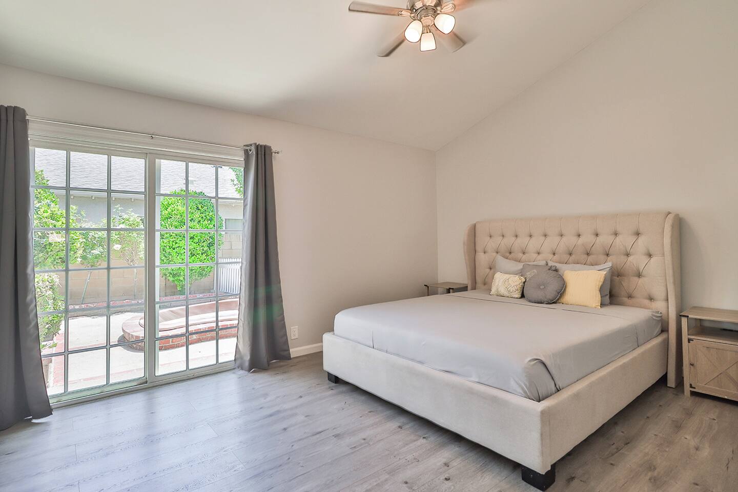 Bathed in gentle light from the large glass doors, king bed masters bedroom with its elegant tufted bed and soothing neutral tones, creates an alluring and comforting sanctuary.