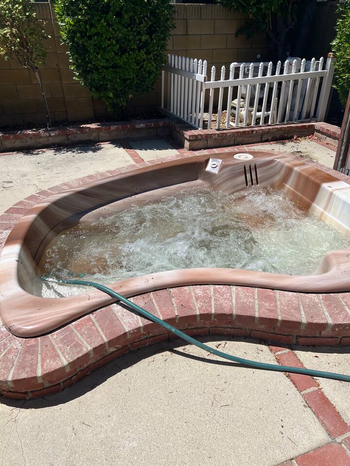 jacuzzi with a red brick border sits on a concrete patio