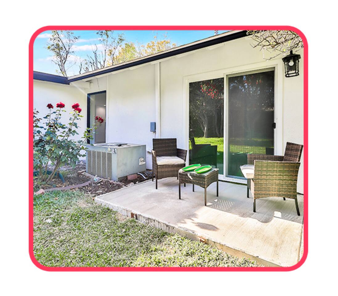 Relaxing concrete patio area featuring dark wicker furniture with white cushions, a small matching side table, and sliding glass door access into the home.