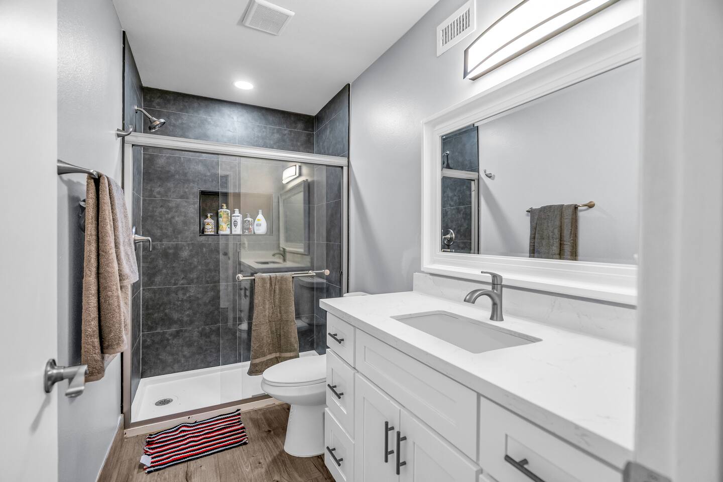 Modern bathroom with dark tile shower and sleek vanity.