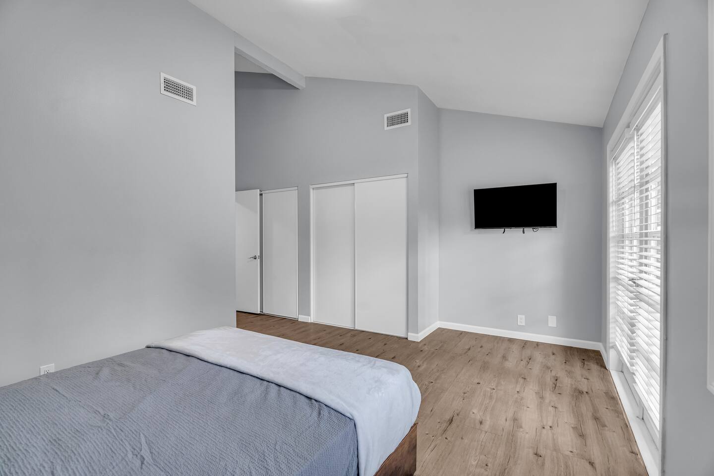 Vaulted bedroom with natural light and smart TV.