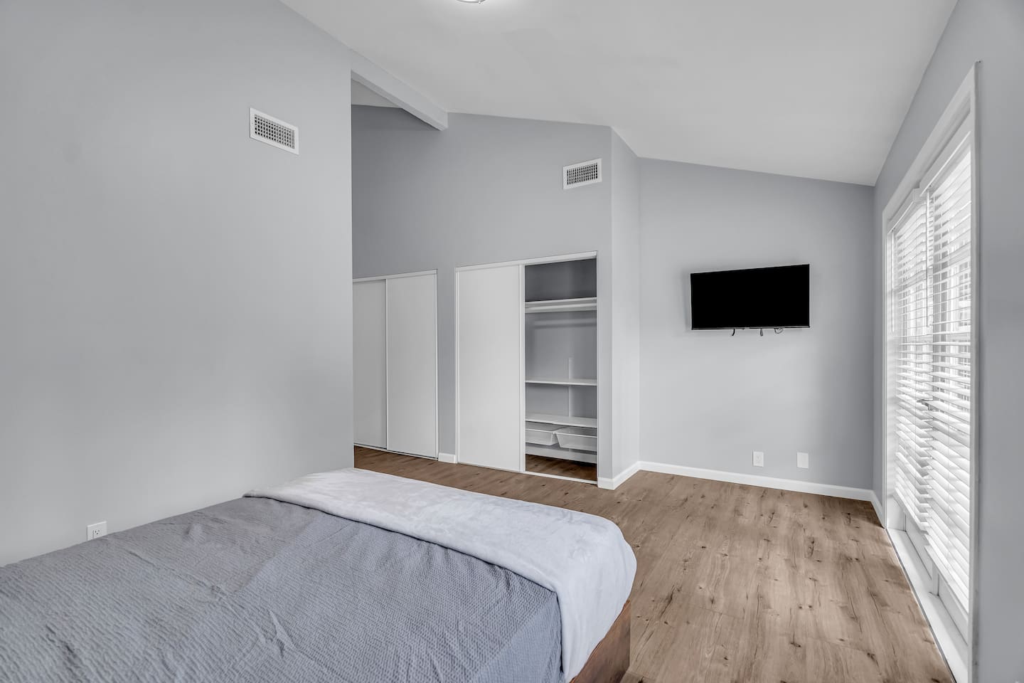 Vaulted bedroom with natural light and smart TV