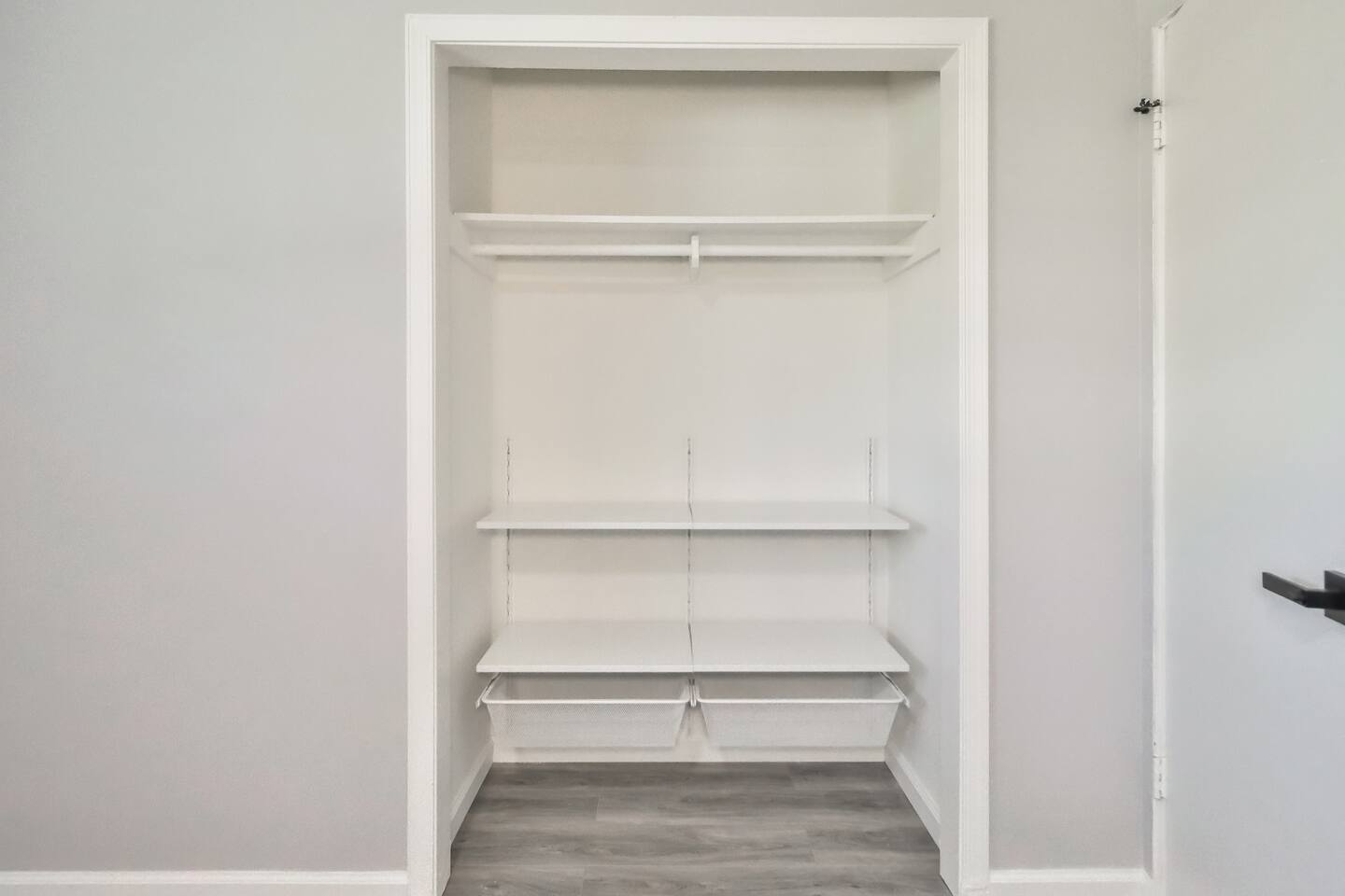 Efficient storage solution featuring a white built-in closet system with adjustable shelving and integrated wire mesh pull-out bins.